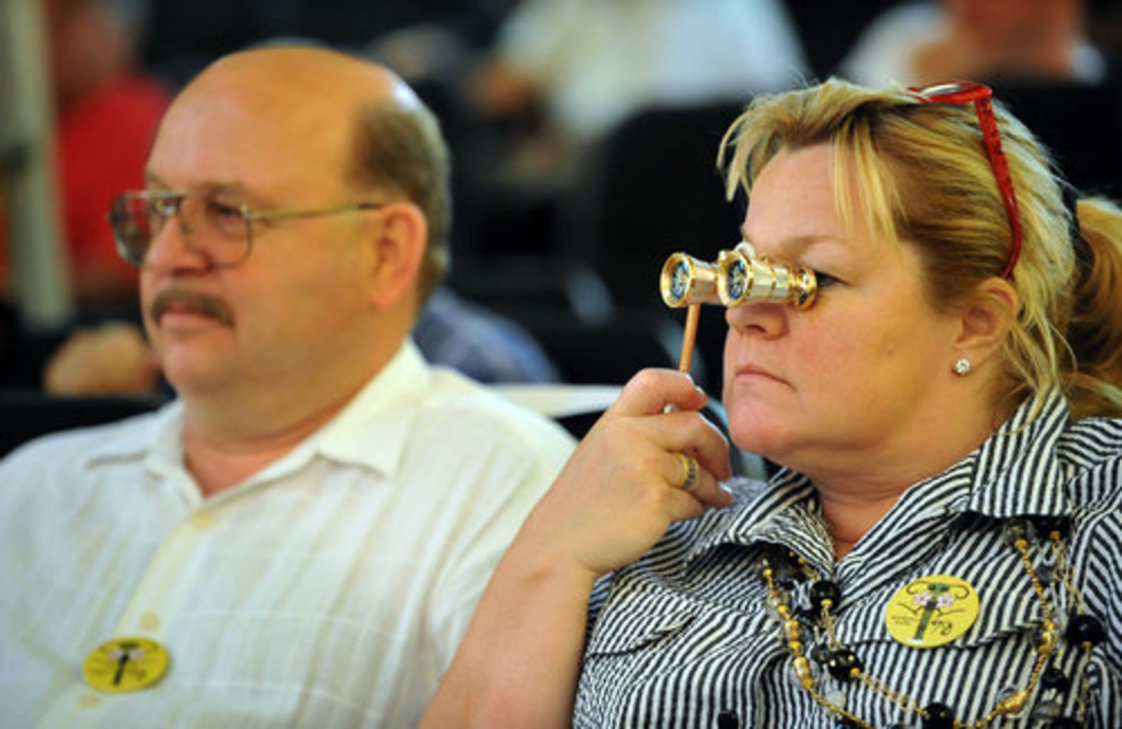 Carter Holland, right, looks an auction item through a binocular as her husband Stephen Holland looks on during the Saturday auction.