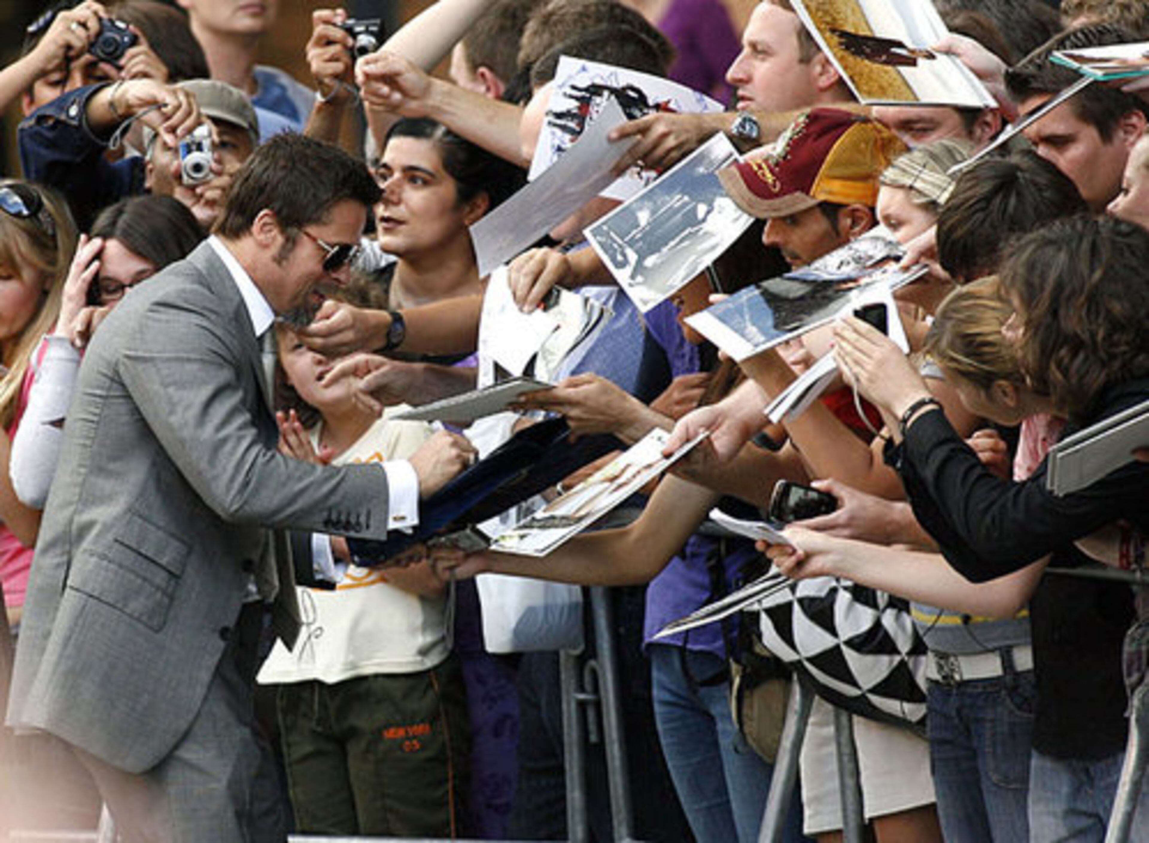 Brad Pitt responds to the request for autographs from fans lined up for the German premiere.