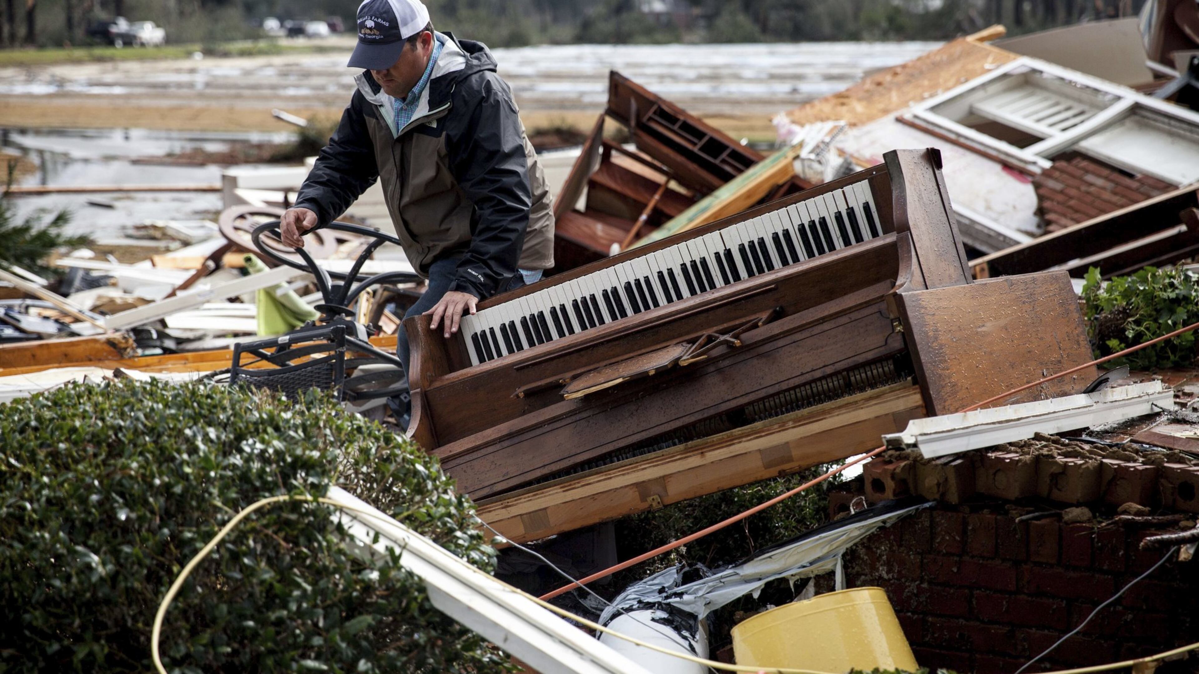 In this Sunday, Jan. 22, 2017, photo, a man walks through debris at a home that was damaged by severe weather in Adel, Ga. (AP Photo/Branden Camp)