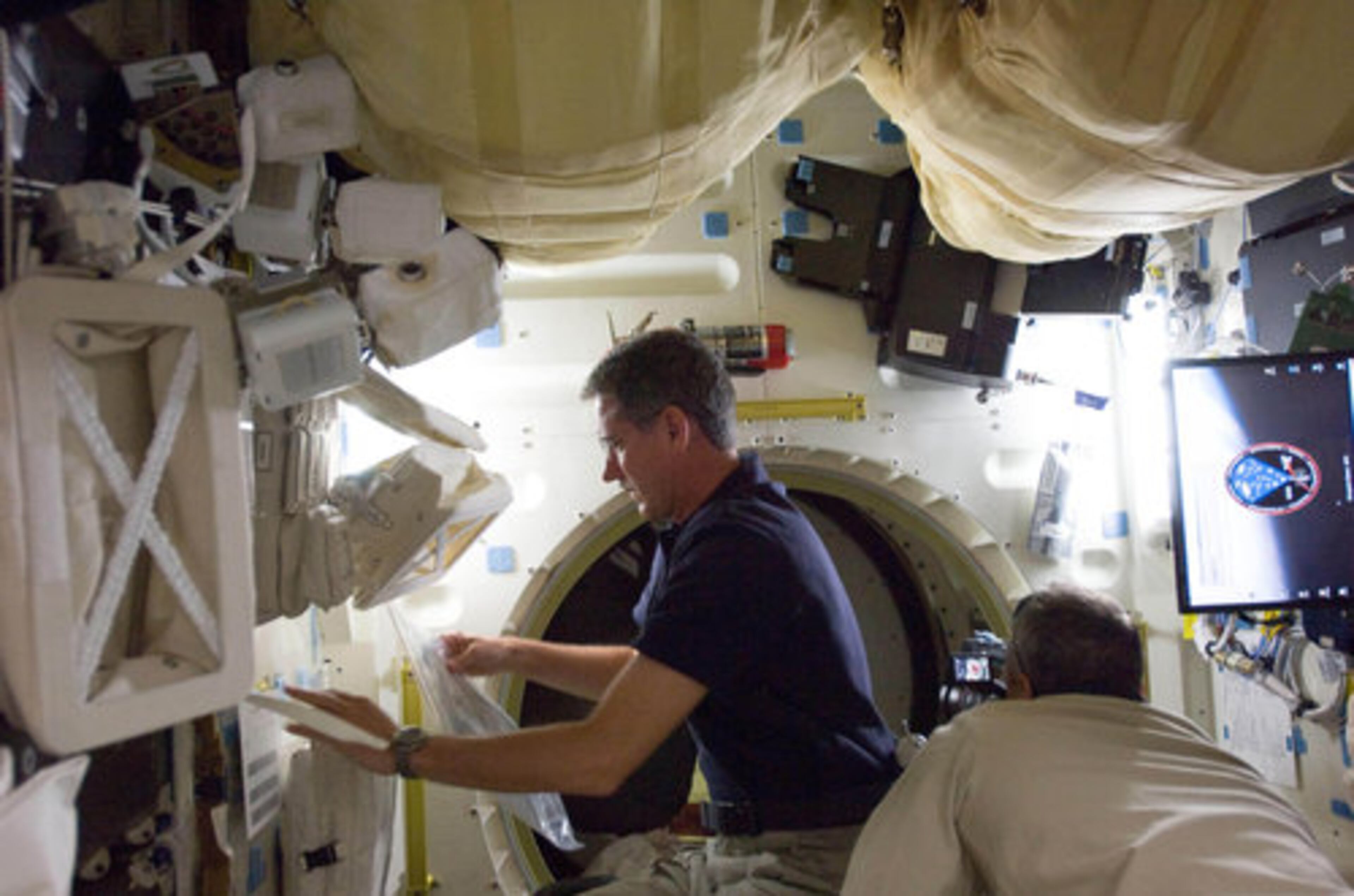 STS-125 mission specialist Michael Good is busy on Atlantis' middeck during his second day in space Wednesday.