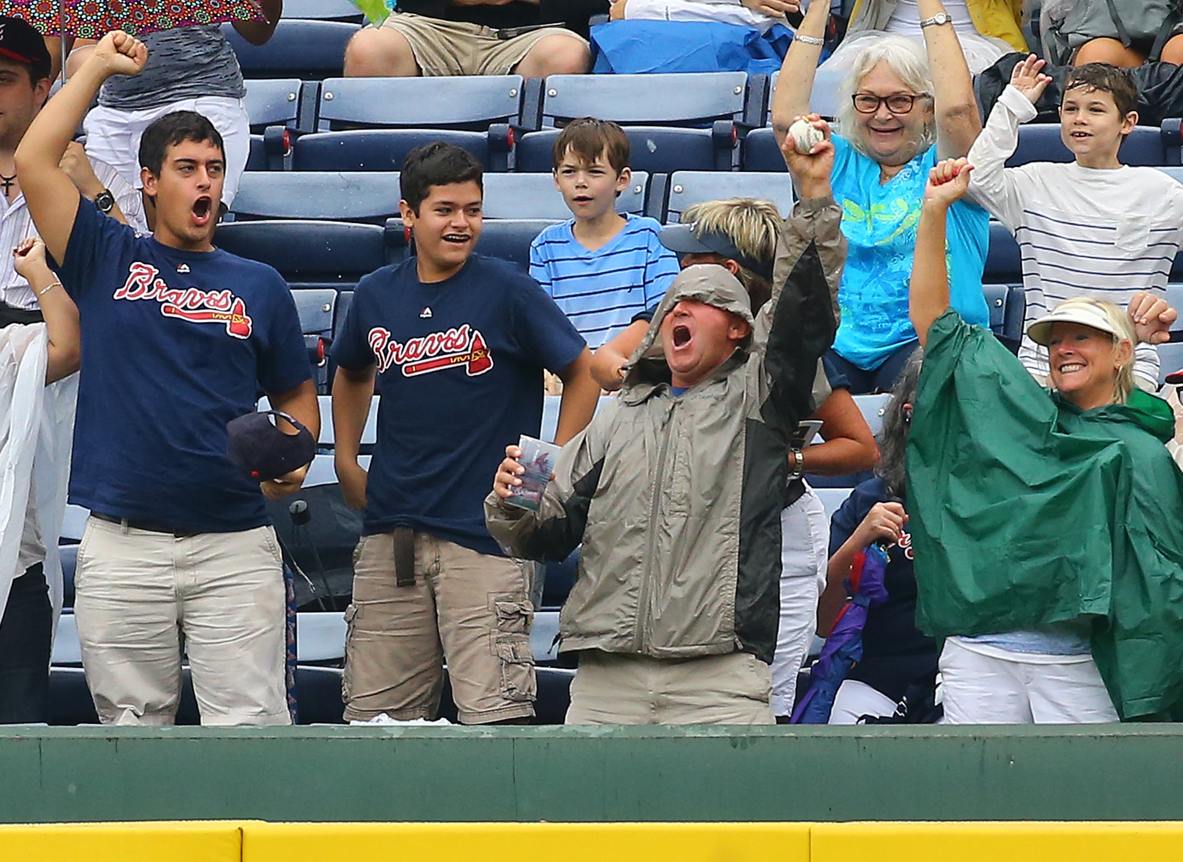 Braves fans, including one who comes up with the ball, react to a 2-run homer by Chris Johnson during the second inning of an MLB game against the Phillies on Sunday, July 20, 2014, in Atlanta. CURTIS COMPTON / CCOMPTON@AJC.COM
