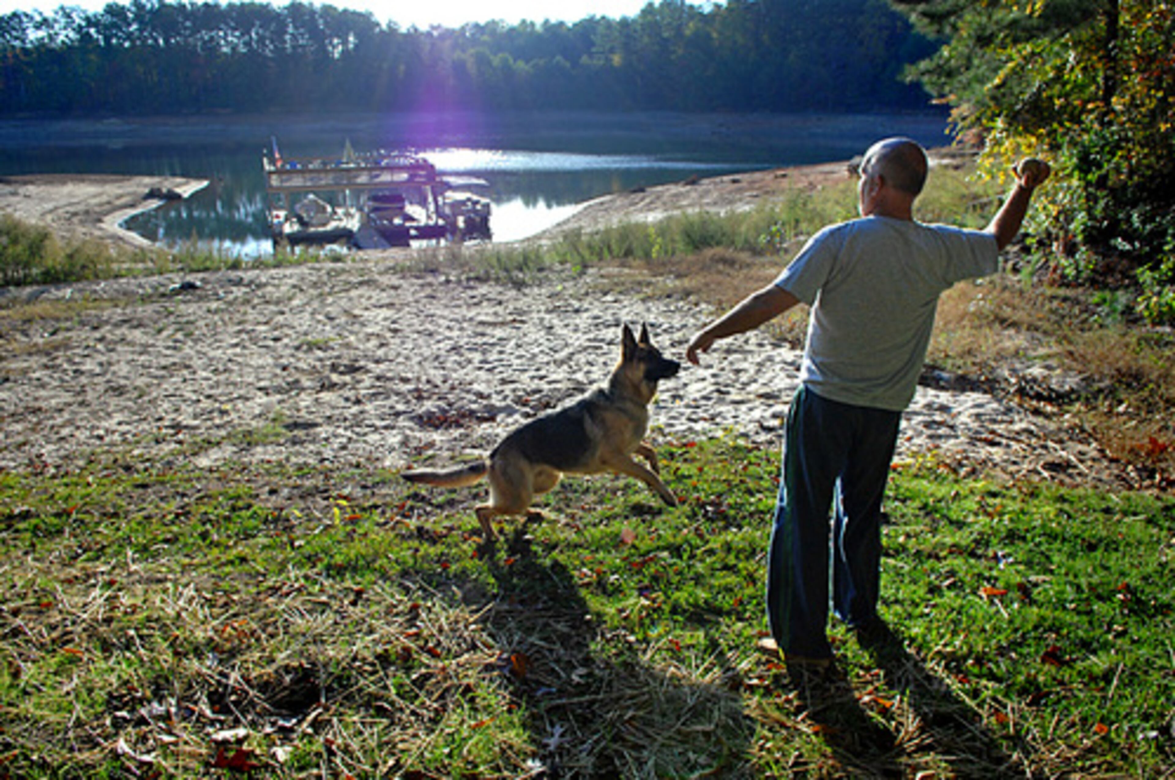 Carl Hansson throws a ball for his dog, Taylor, after his daily check of the water near his dock (background) just off Chattahoochee Bay near the Aqualand Marina. Hansson, who has lived on the lake since 1990, said it's the lowest he's ever seen it. If the lake were at its normal level, Hansson said, he would be standing at water level in this picture.