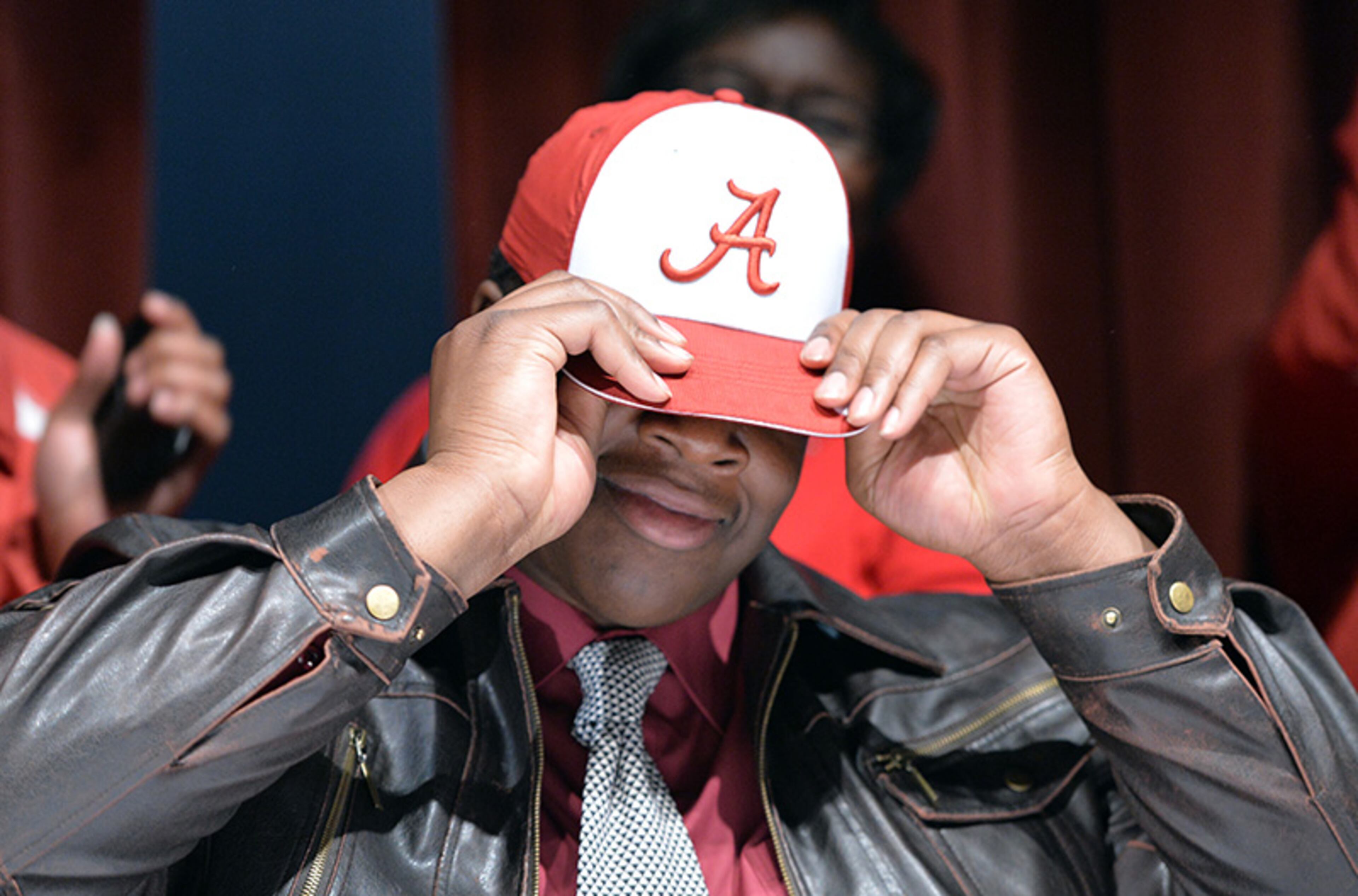 Elisha Shaw puts on an Alabama hat as he announces his college during signing day festivities at Tucker High School.