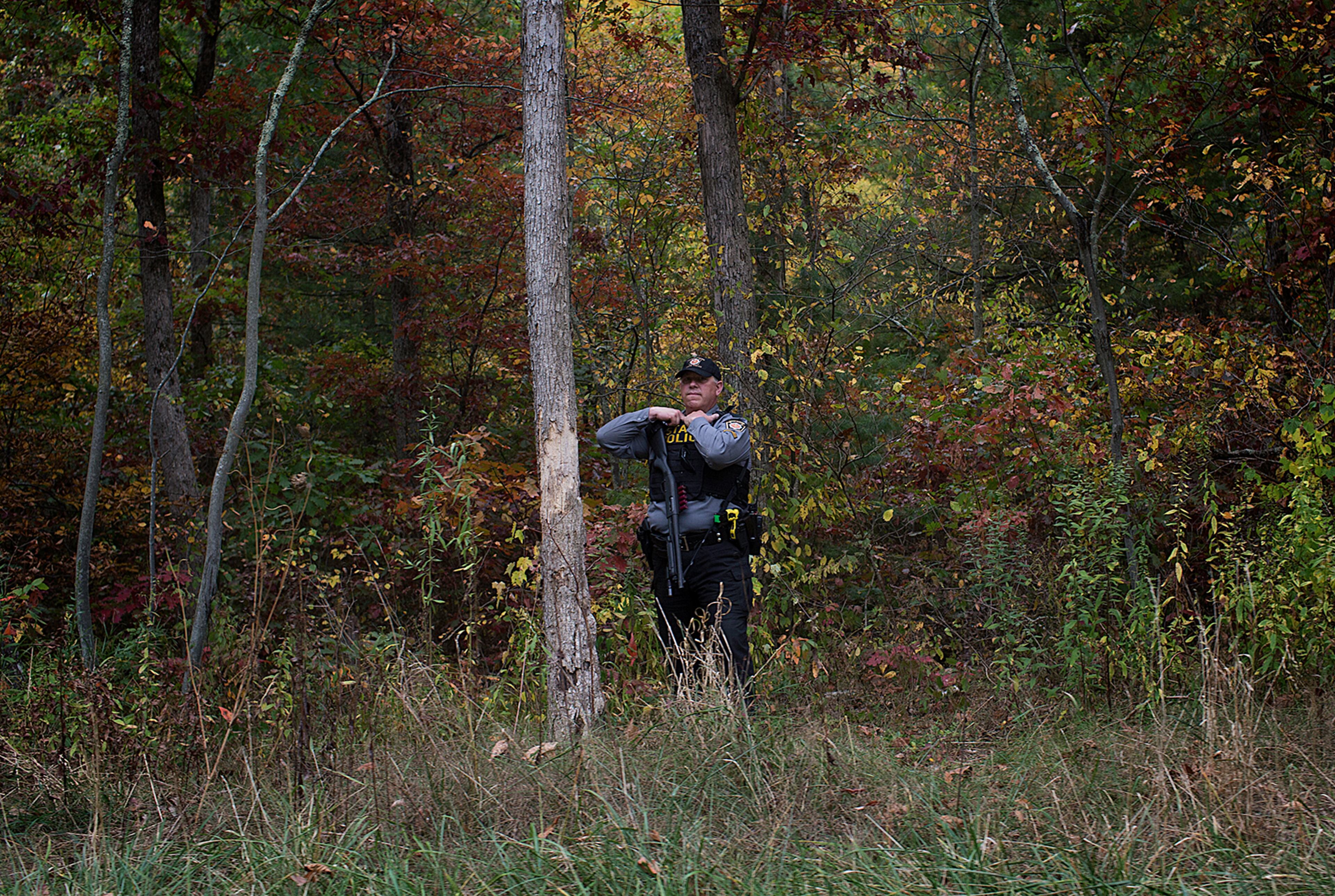 A Trooper patrols the woods along Rt. 447 in Monroe Twp., Pa., searching for Eric Frein on Wednesday, Oct. 1, 2014. Frein, 31, is accused of killing Cpl. Bryon Dickson, 38, and critically wounding Trooper Alex Douglass outside outside the Blooming Grove barracks on Sept. 12. (AP Photo/PennLive.com, Sean Simmers)