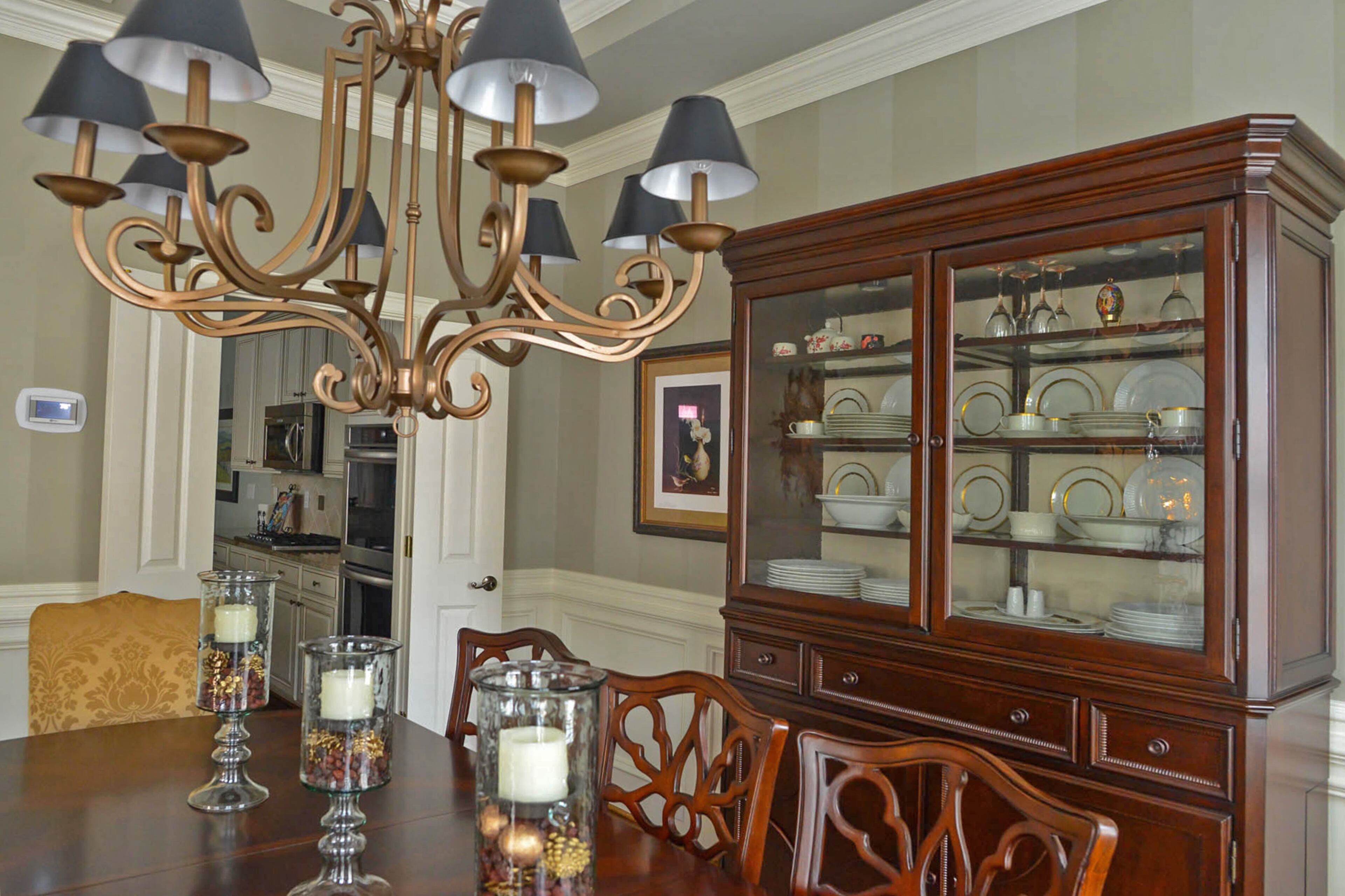 The vertical striped accent wall uses Sherwin-Williams' Gateway Gray in two sheens, eggshell and gloss, for a decorative look above the chair rail. The dining room is outfitted with a table, chairs and hutch from Bassett Furniture. The sunburst mirror and metal chandelier add another finish to the room.