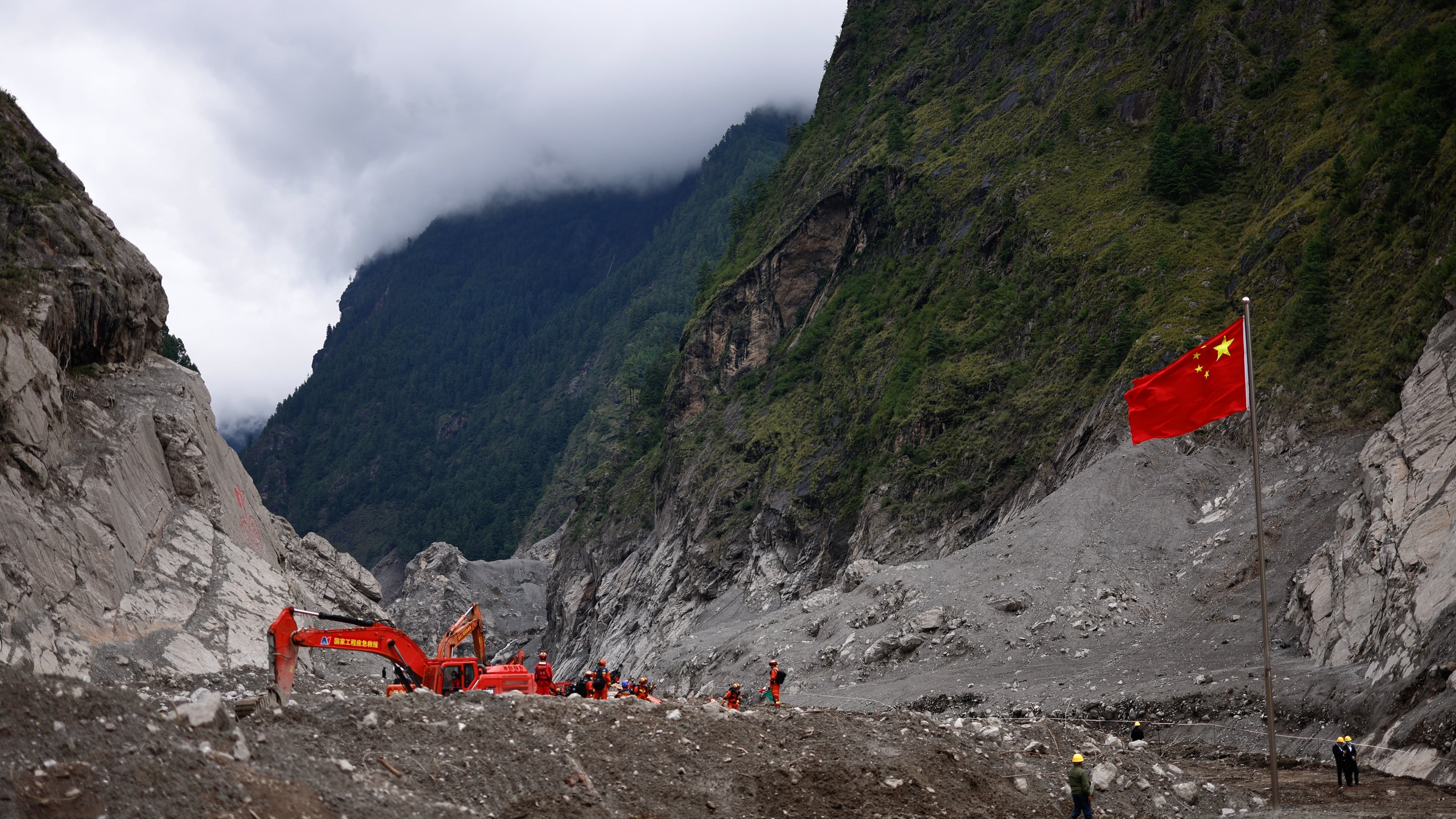 Rescue workers conduct search and rescue operations, near a Chinese national flag, at the core disaster-hit area at Gyirong Port amid rescue efforts following the August 26 mudslide, during an organised media tour in Shigatse, Tibet Autonomous Region, China, Sunday, Sept. 6, 2026. (Tingshu Wang/Pool Photo via AP)