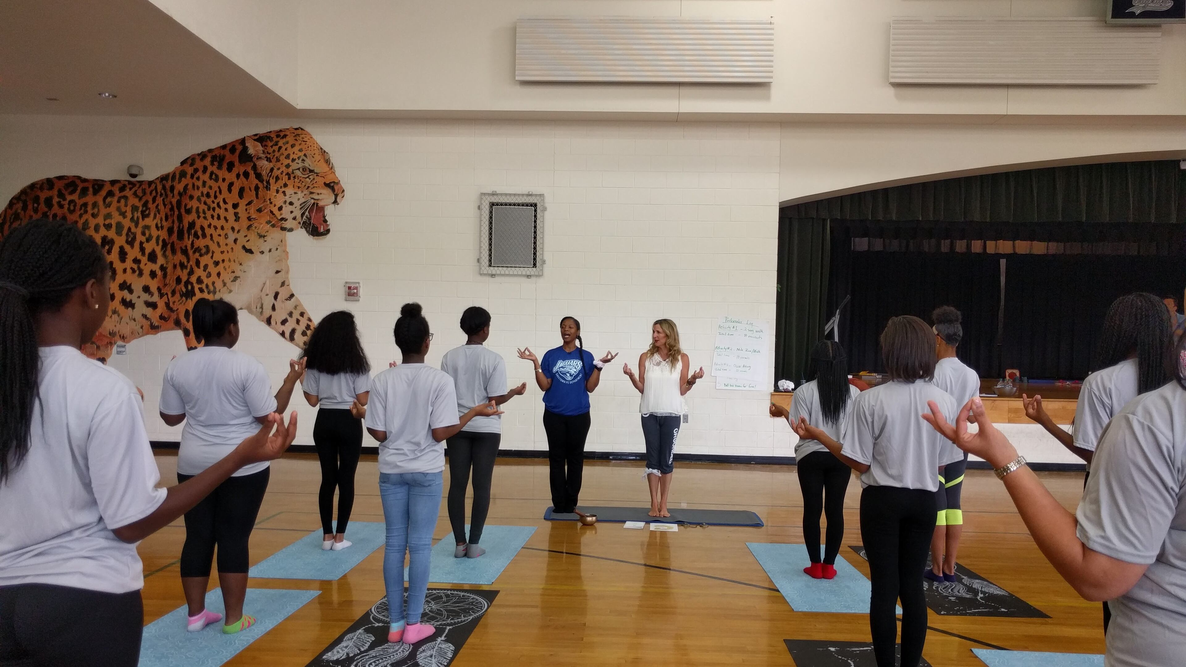 May 18, Atlanta: Cheryl Crawford ( center right), of Grounded Kids Yoga, leads Sandtown Middle School students in yoga with P.E. teacher Tracy Baker (next to her in blue shirt), a former science teacher who will be teaching yoga full-time at the school in the fall after earning her yoga teaching credential from Crawford. This session at the Fulton County school's gym was a practice run.
