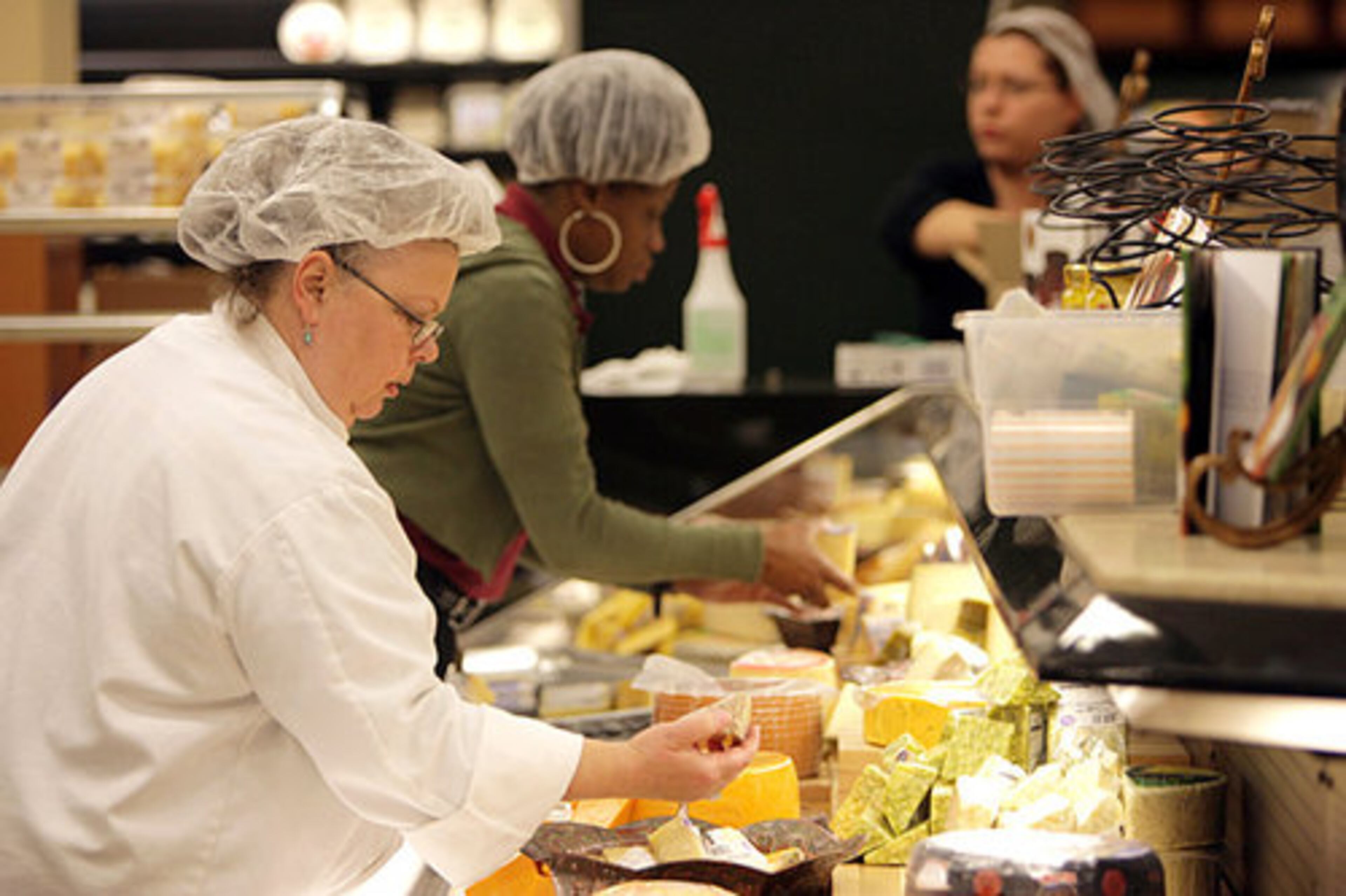 Karen Jorgensen (left) and Rhonda Cohn set out some of Fresh Fare's selection of imported cheeses.
