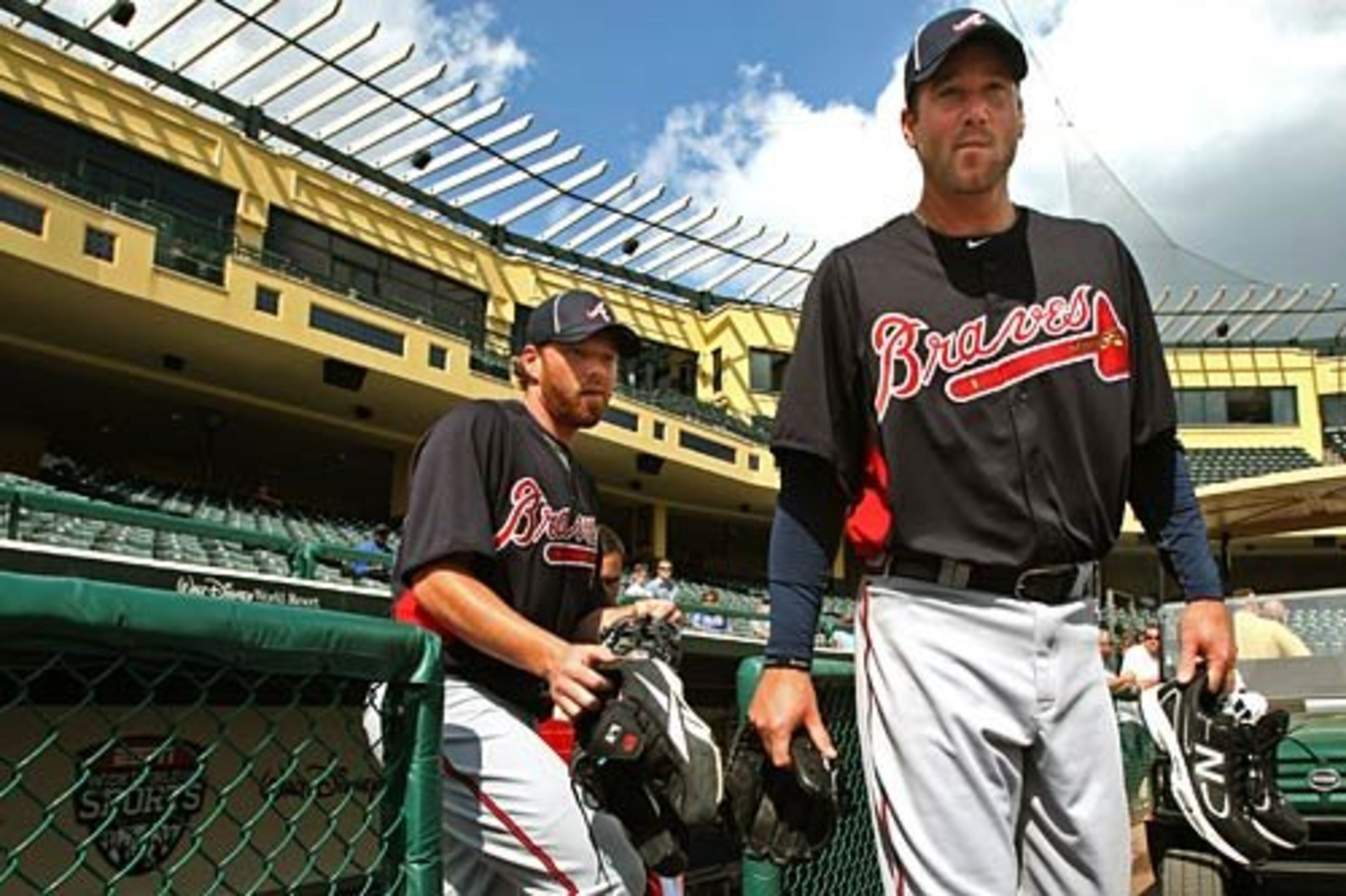 Braves starting pitchers Tommy Hanson, left, and Derek Lowe carry their gear onto the field as practice begins.