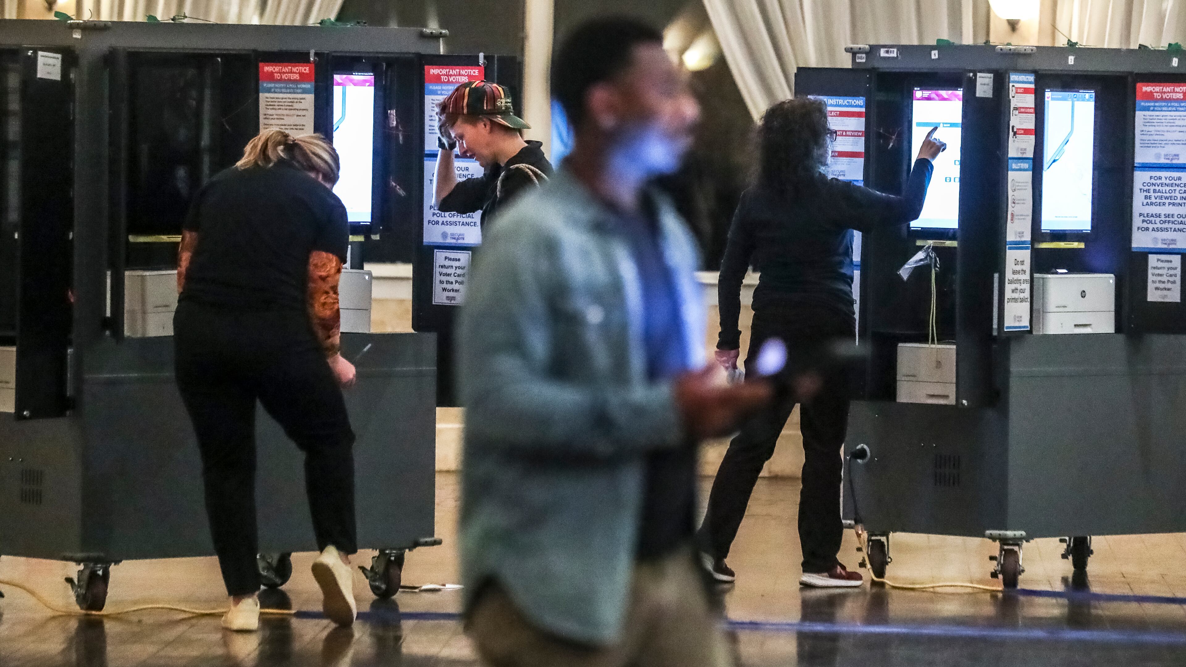 Poll workers (left to right) Alexandra Almeter, Gamble Everett, Erik Coleman and Sarah Zaslaw prepare voting machines before the polls opened on Tuesday, Dec. 6, 2022 at Park Tavern in Atlanta. (John Spink / John.Spink@ajc.com)
