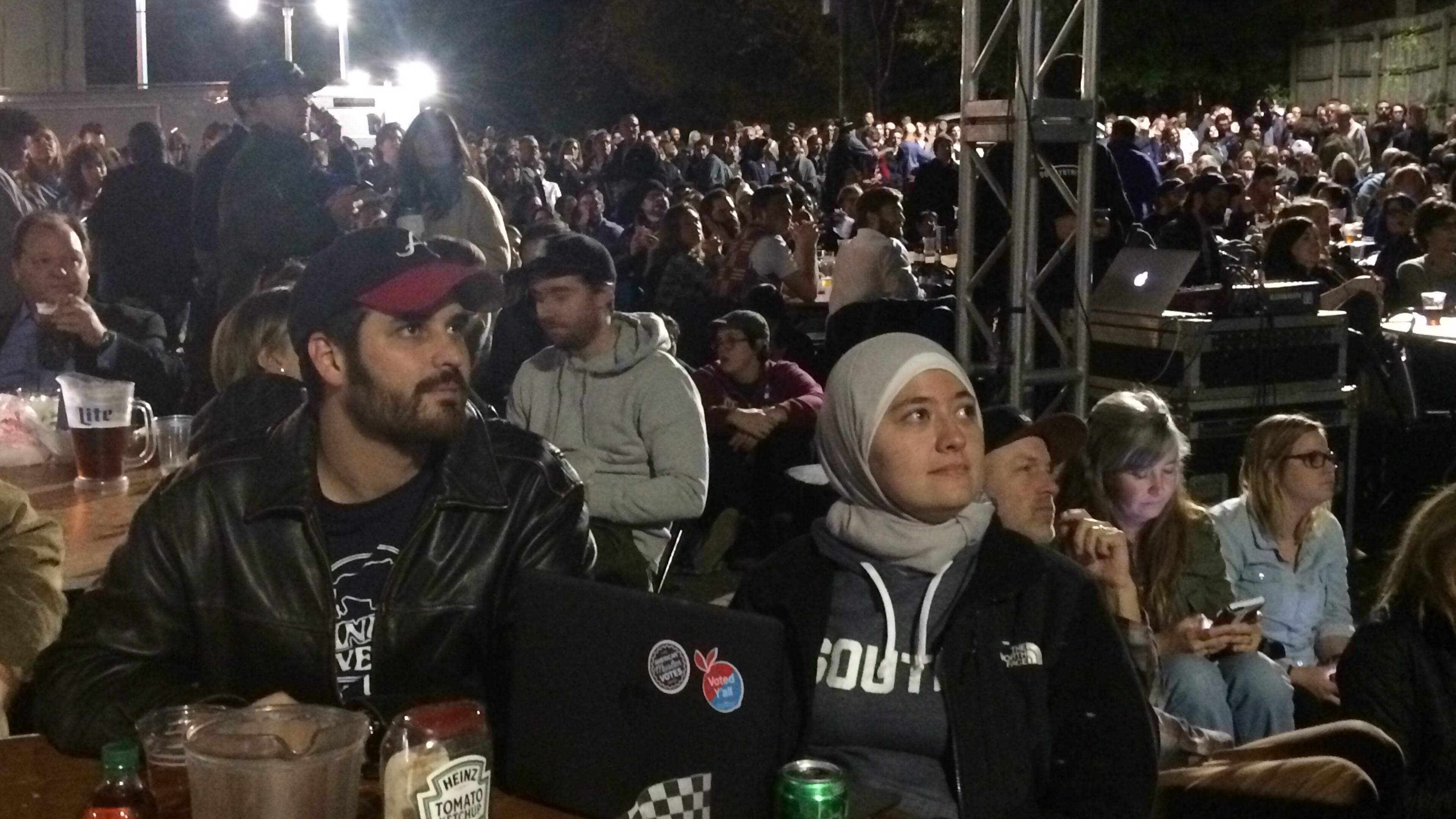 Corey Ray and Ruwa Romman watch election results outside at Manuel's Tavern. Photo: Jennifer Brett, jbrett@ajc.com