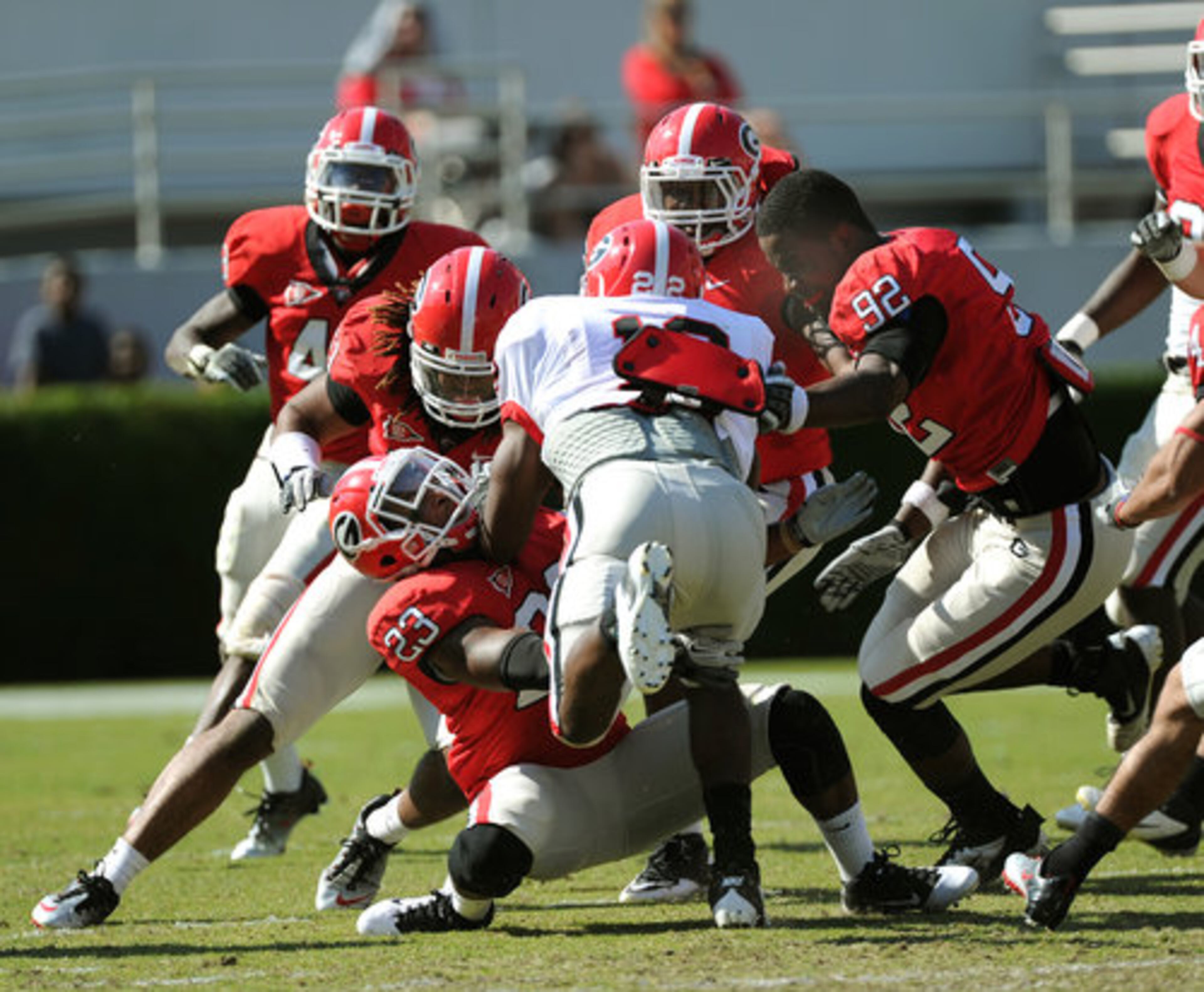 (right)UGA's Dexter Morant (92) looses his helmet as he helps his teammates tackle Richard Samuel IV (center) during the UGA Spring Football Game in Sanford Stadium at the University of Georgia on Saturday, April 14, 2012. The Red team won 32 to 31.