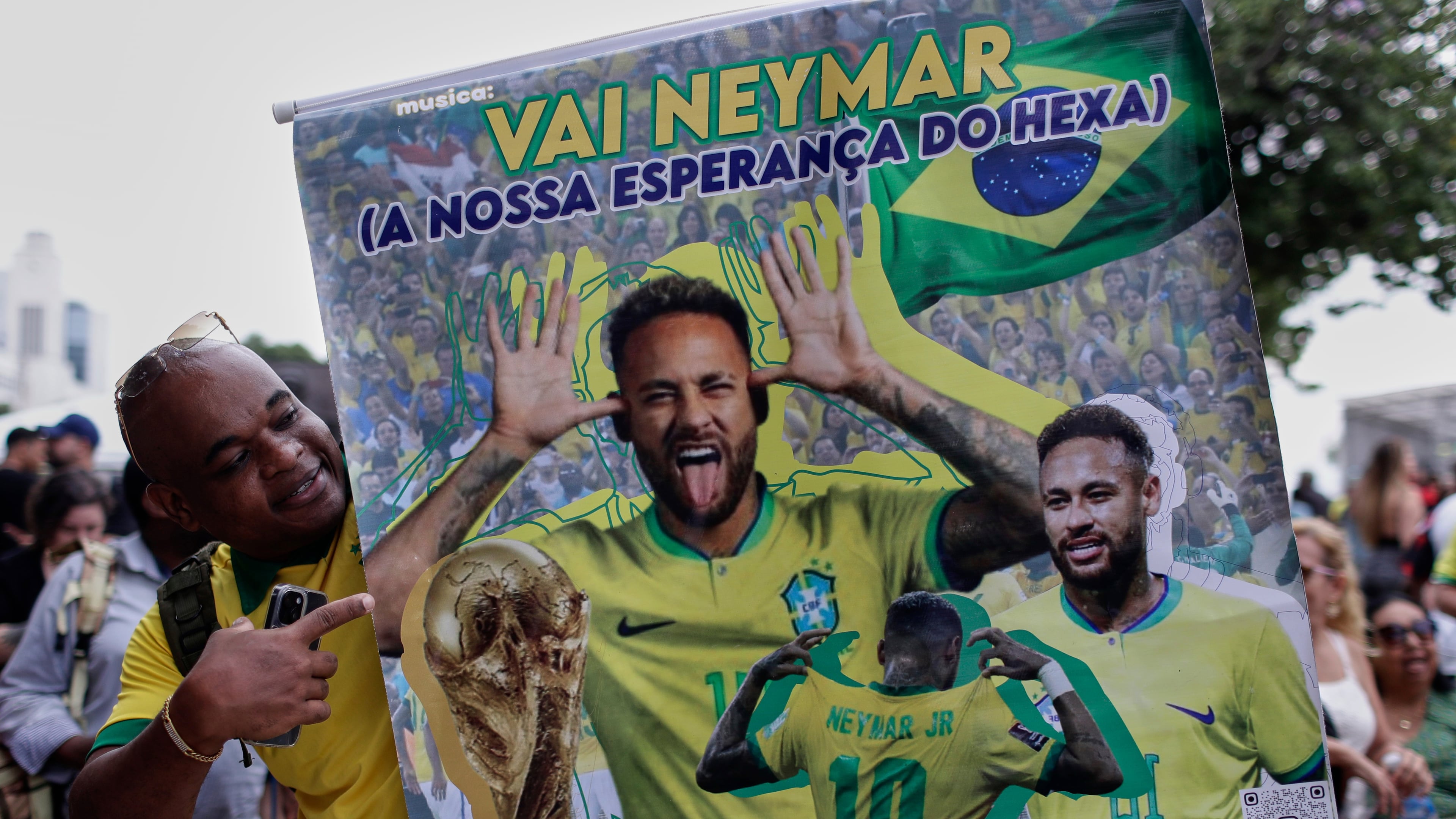 A fan poses with a poster of Brazilian soccer player Neymar, reading in Portuguese "Go Neymar, our hope for a sixth World Cup title" before Brazil's 2026 World Cup squad is announced, in Rio de Janeiro, Monday, May 18, 2026. (AP Photo/Bruna Prado)