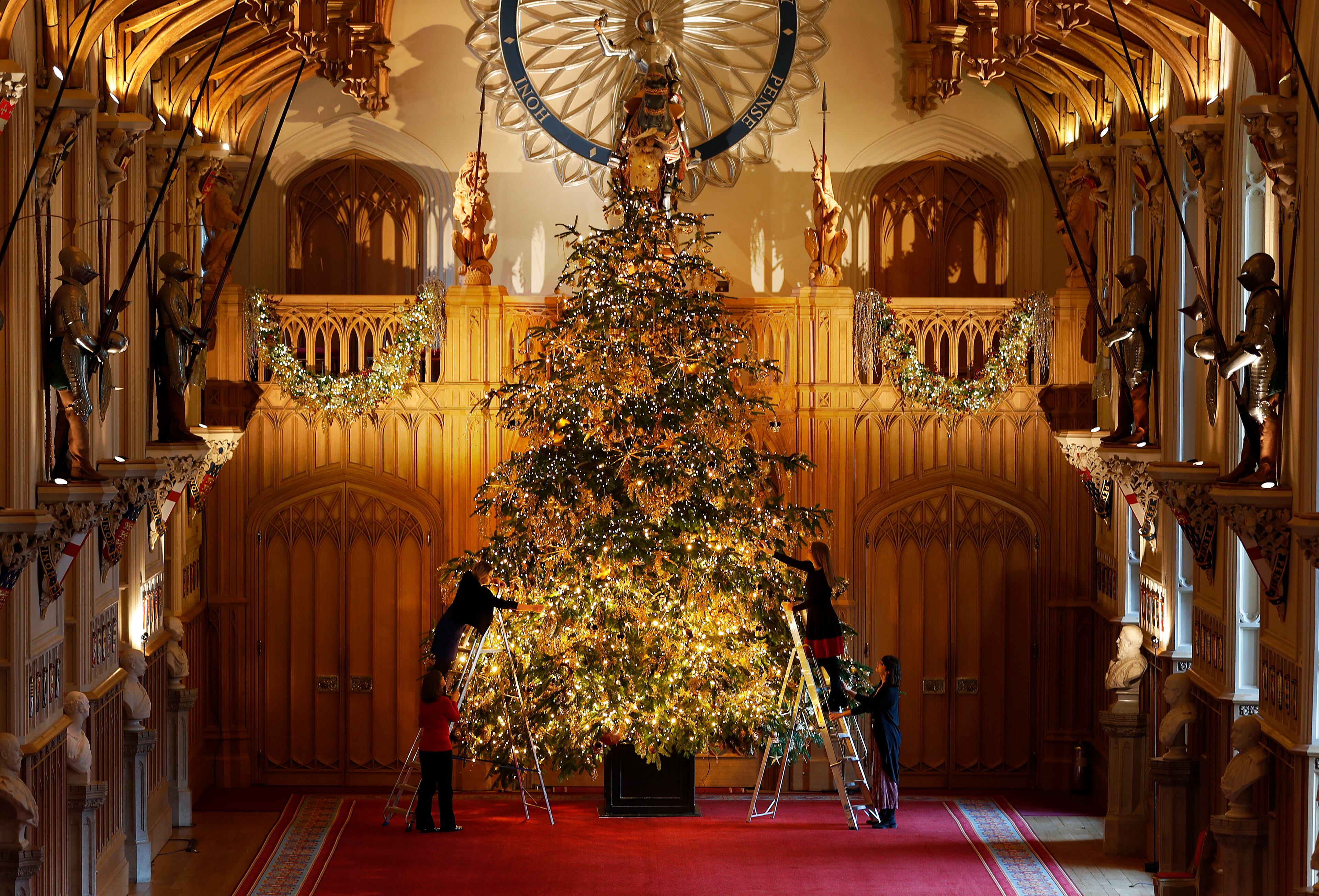 A 20ft Nordmann Fir tree from Windsor Great Park, entirely dressed in gold, is decorated and stands at the end of St George's Hall, at Windsor Castle in Windsor, England, Friday, Nov. 30, 2018. (AP Photo/Frank Augstein)