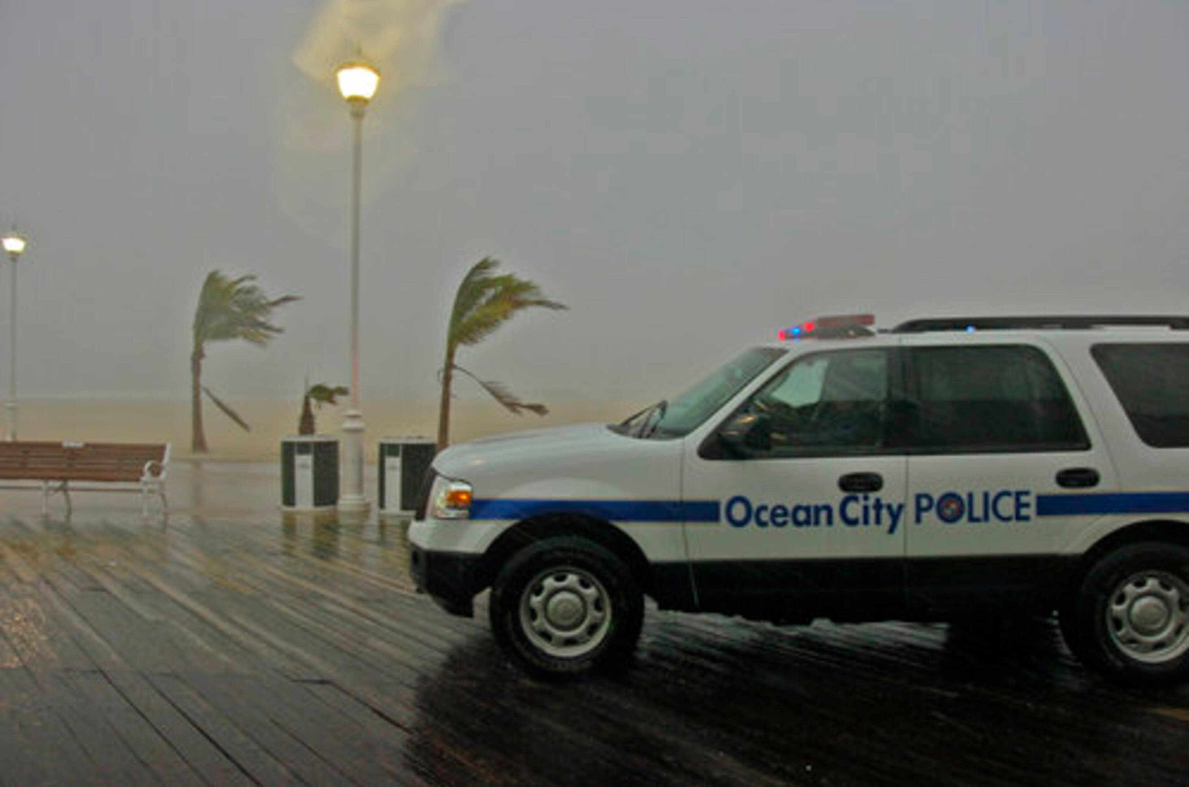 Palm trees bow from storm gusts as a police vehicle patrols the boardwalk as rain and winds preceding the full impact of Hurricane Irene hit Ocean City, Maryland, Saturday, August 27, 2011.