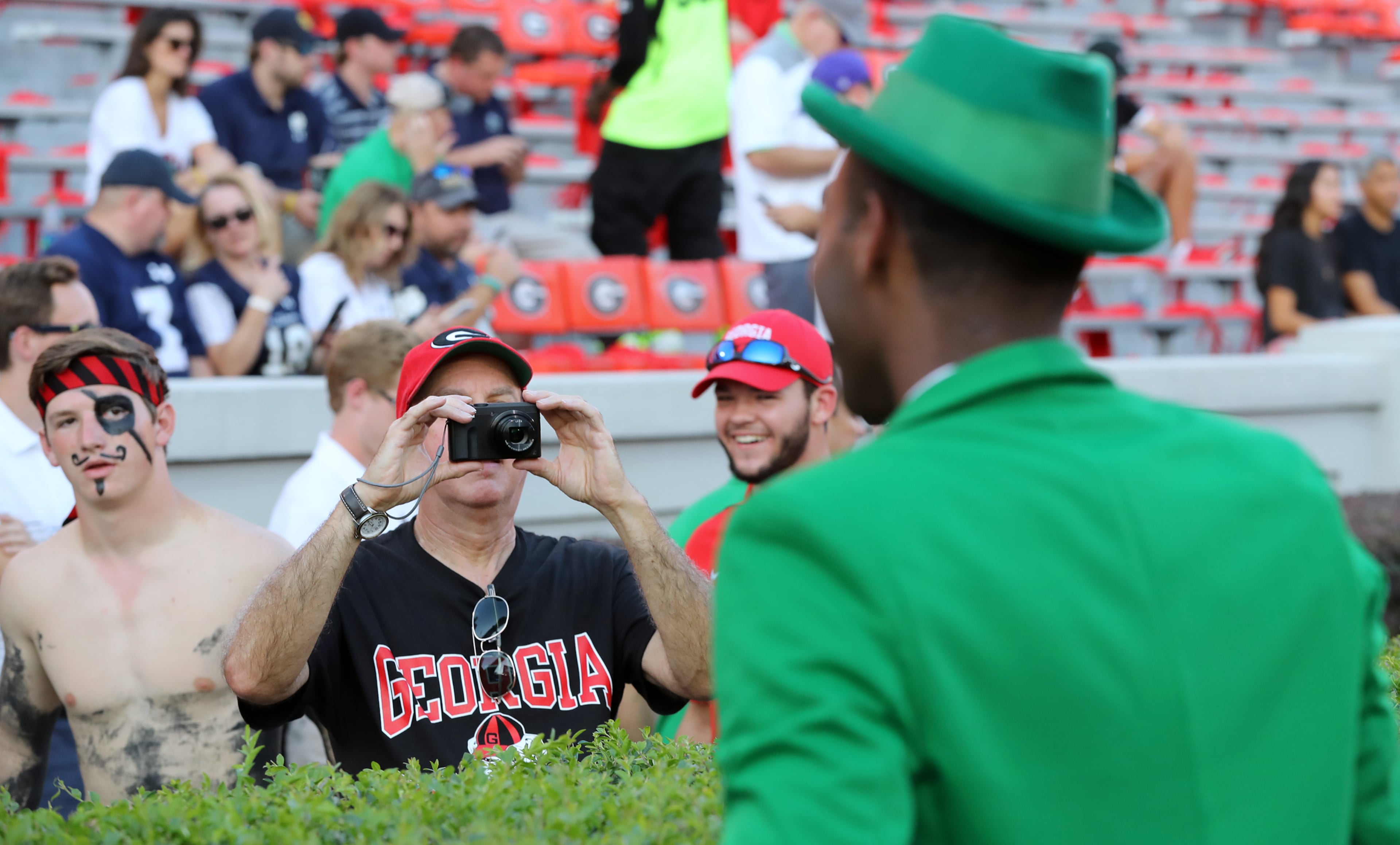 A Georgia fan (far left) gives Notre Dame mascot leprechaun Sam the stink eye while another snaps his picture before the teams face off. Curtis Compton/ccompton@ajc.com