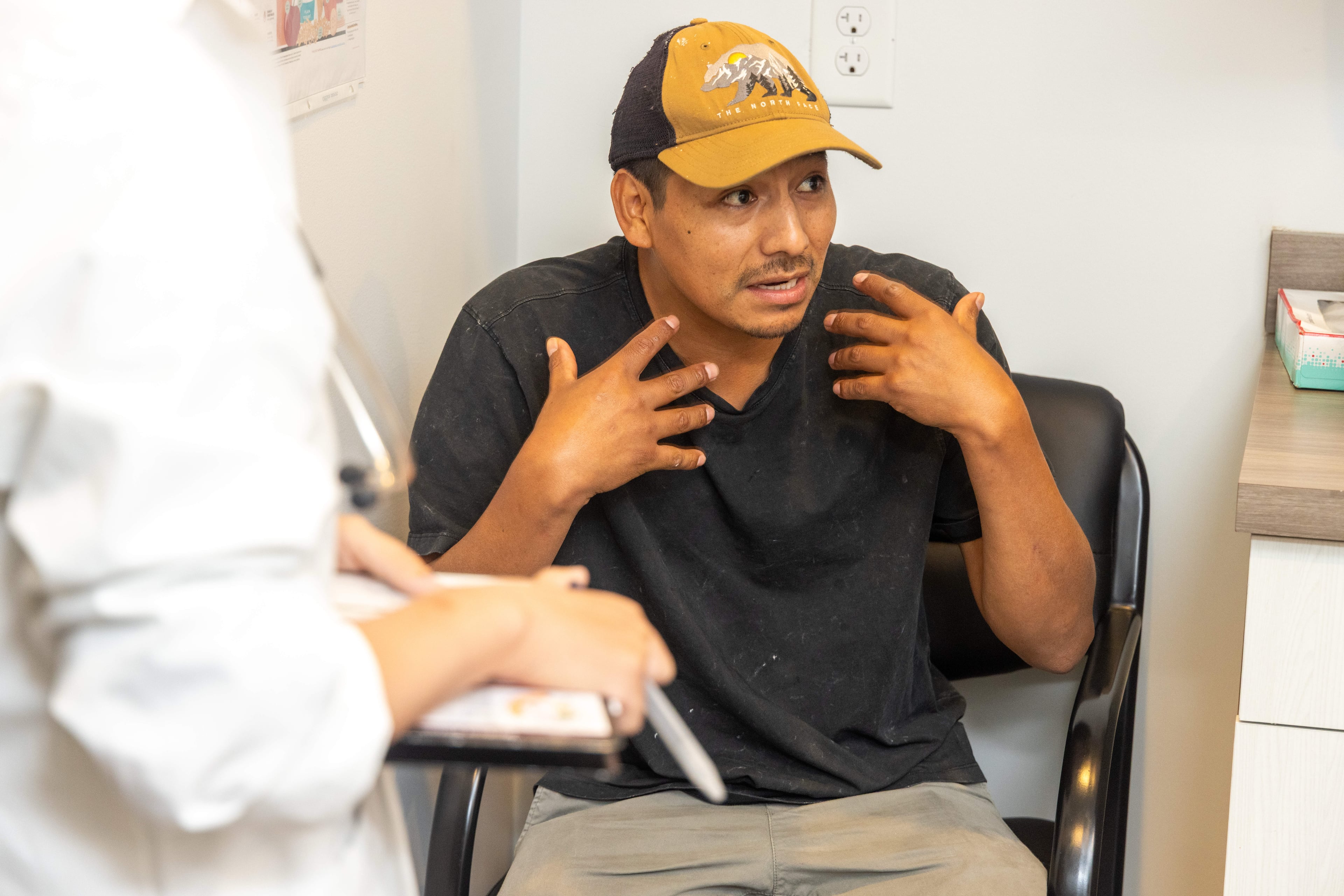 Peregrino Fernandez explains his issue to interpreter Maria Elan during a visit to the Forsyth Community Clinic, a free health care clinic for uninsured adults in Forsyth County. (Phil Skinner for the AJC)