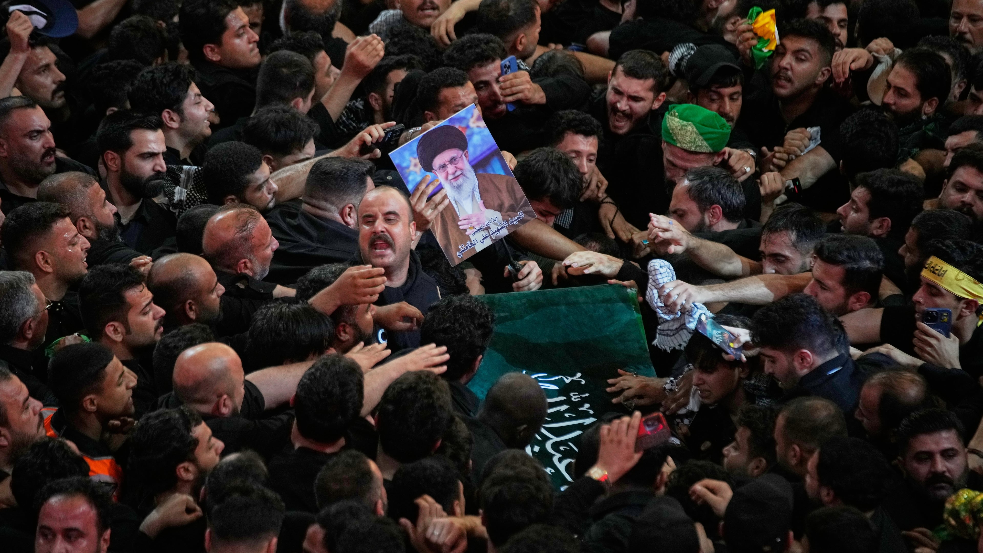 The coffin of the late Iranian Supreme Leader Ayatollah Ali Khamenei is carried through a tightly packed crowd as mourners jostle to reach and touch it outside the Imam Hussein Shrine in Karbala, Iraq, early Thursday, July 9, 2026. (AP Photo/Khalil Hamra)