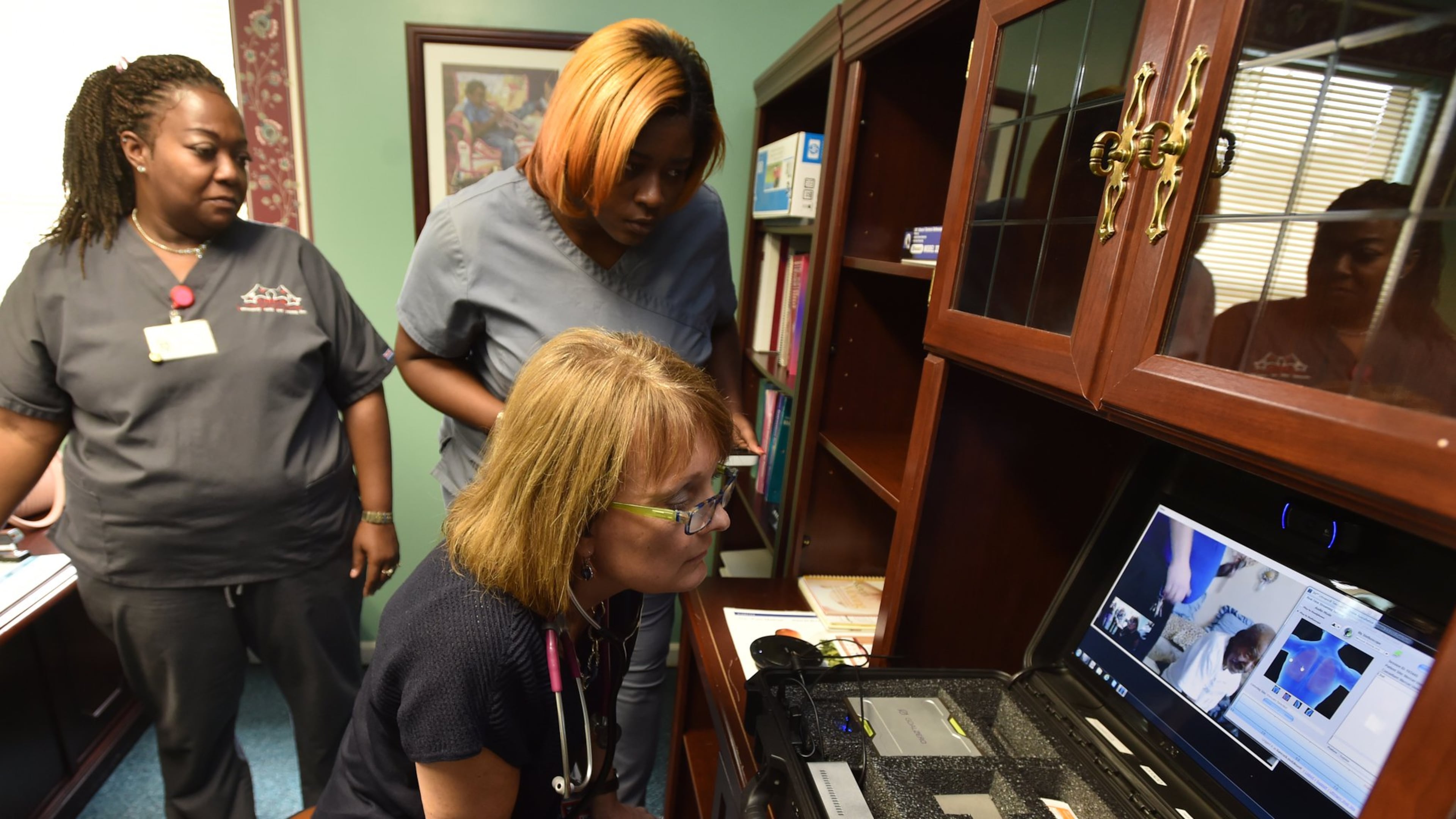 At the Community Health Care Systems center on Hamilton Street in Sparta, Ga., nurse practitioner Kemberly Smith (foreground) and medical assistants Keisha Hill and Joy Robinson examine a patient via telemedicine on Aug. 27, 2015. BRANT SANDERLIN /BSANDERLIN@AJC.COM
