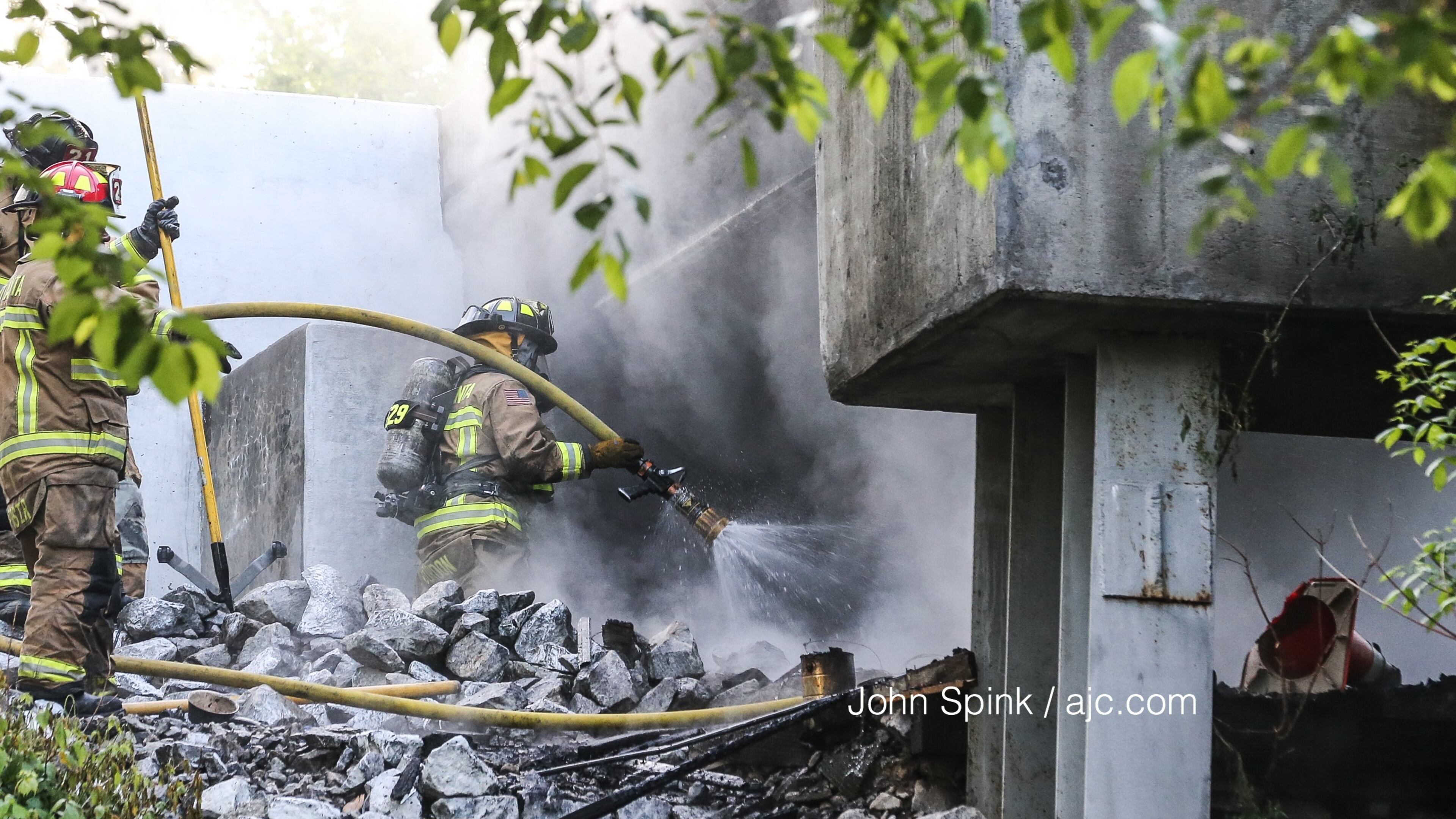 Crews worked to put out a fire under railroad bridge near Cheshire Bridge Road in Buckhead. JOHN SPINK / JSPINK@AJC.COM