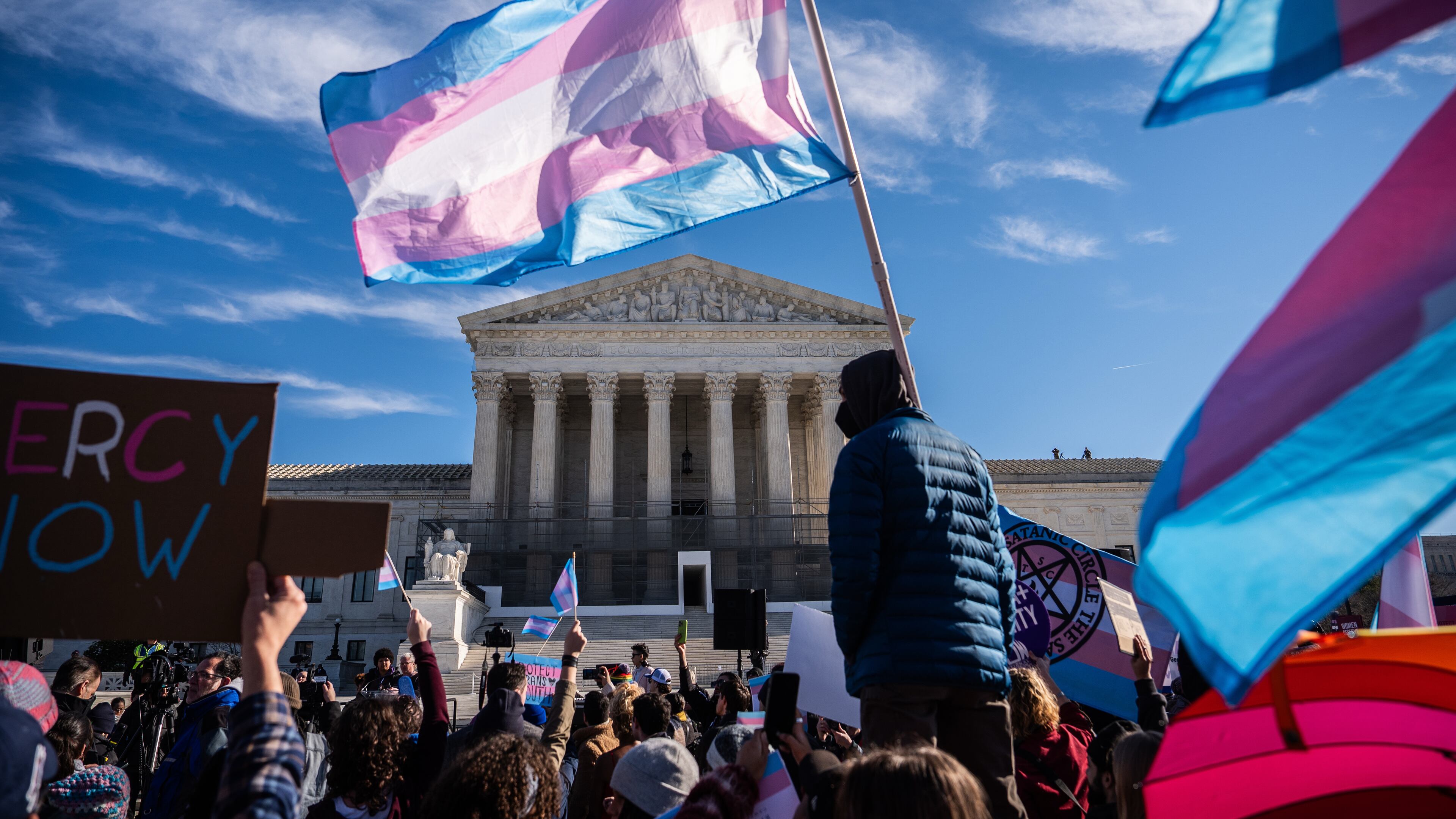 Protesters wave transgender pride flags outside the Supreme Court as it hears arguments over state laws barring transgender girls and women from playing on school athletic teams, Tuesday, Jan. 13, 2026, in Washington. (AP Photo/Julia Demaree Nikhinson)