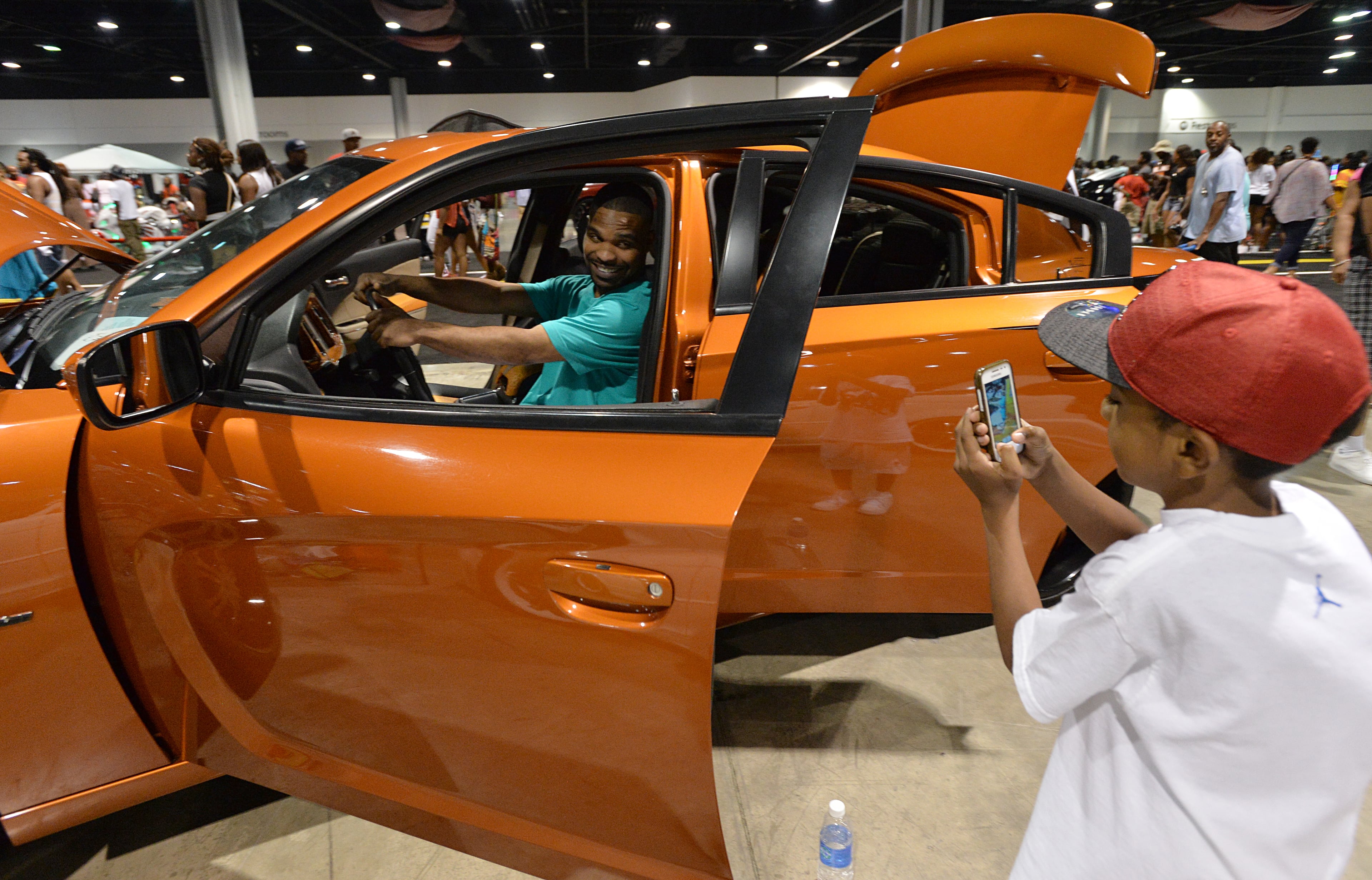 Shawn Hunton, of Atlanta, poses as his nephew Amirzell Williams (right), 9, takes a picture during The 2014 V-103/WAOK Car & Bike Show at the Georgia World Congress Center on Saturday, July 12, 2014.