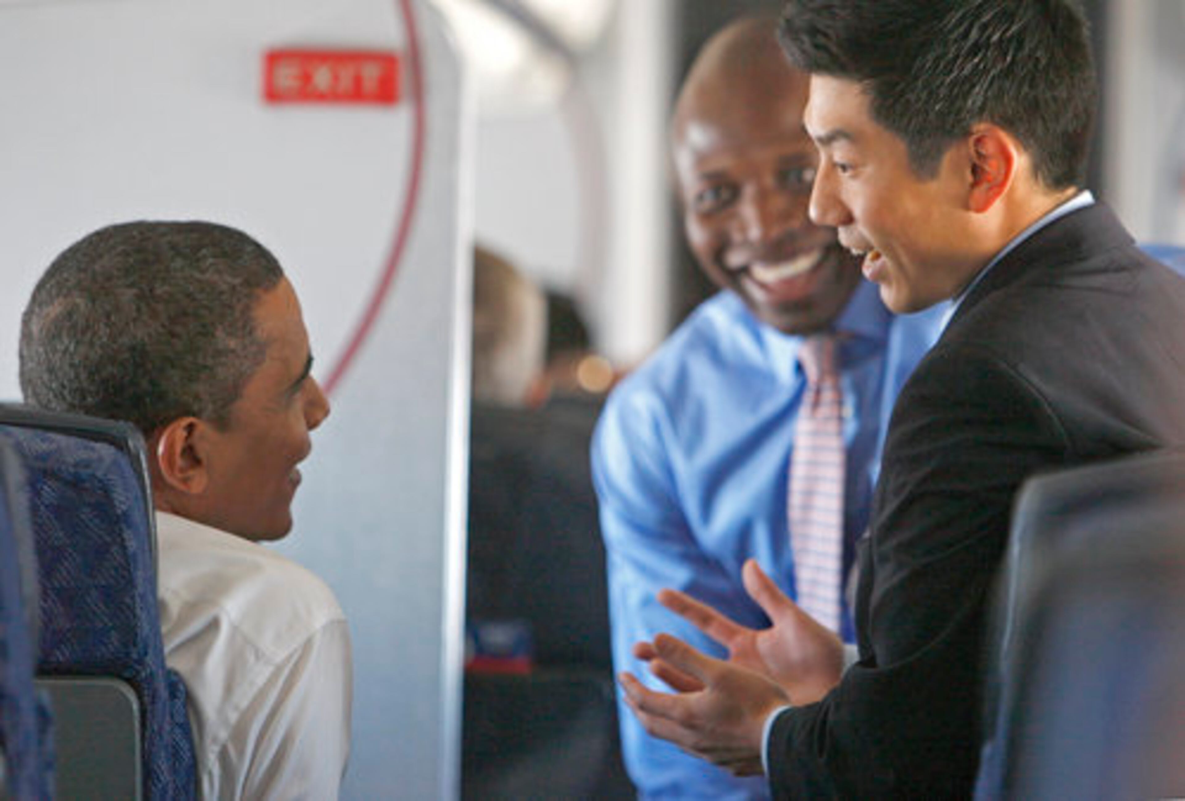 President-elect Obama, left, speaks with aide Reggie Love, center, and adviser Eugene Kang on his American Airlines flight from Chicago to Washington D.C. on Monday, where he will meet with President Bush at the White House.
