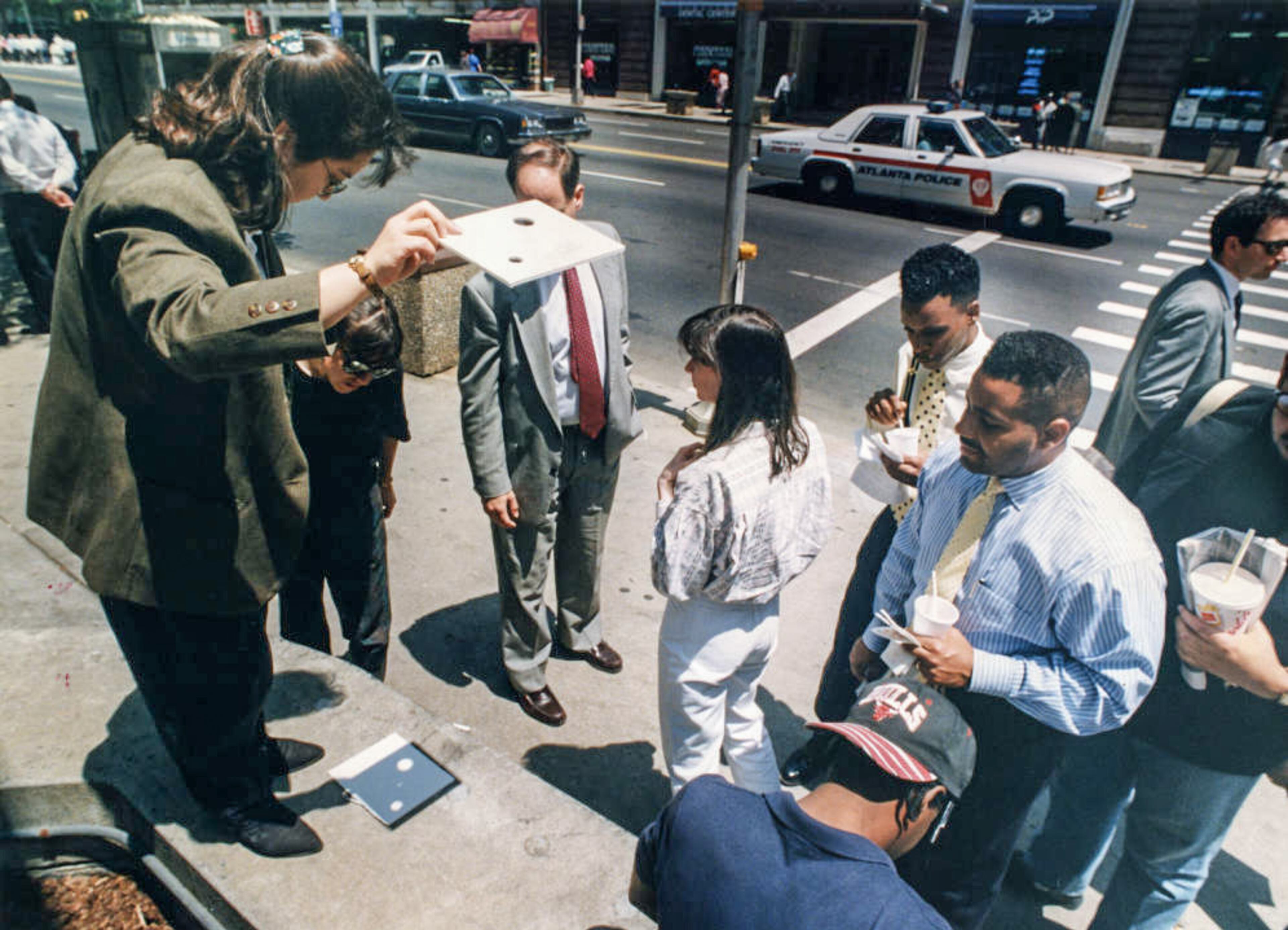 Office workers taking a break to watch the solar eclipse through a pinhole projection, May 1994.