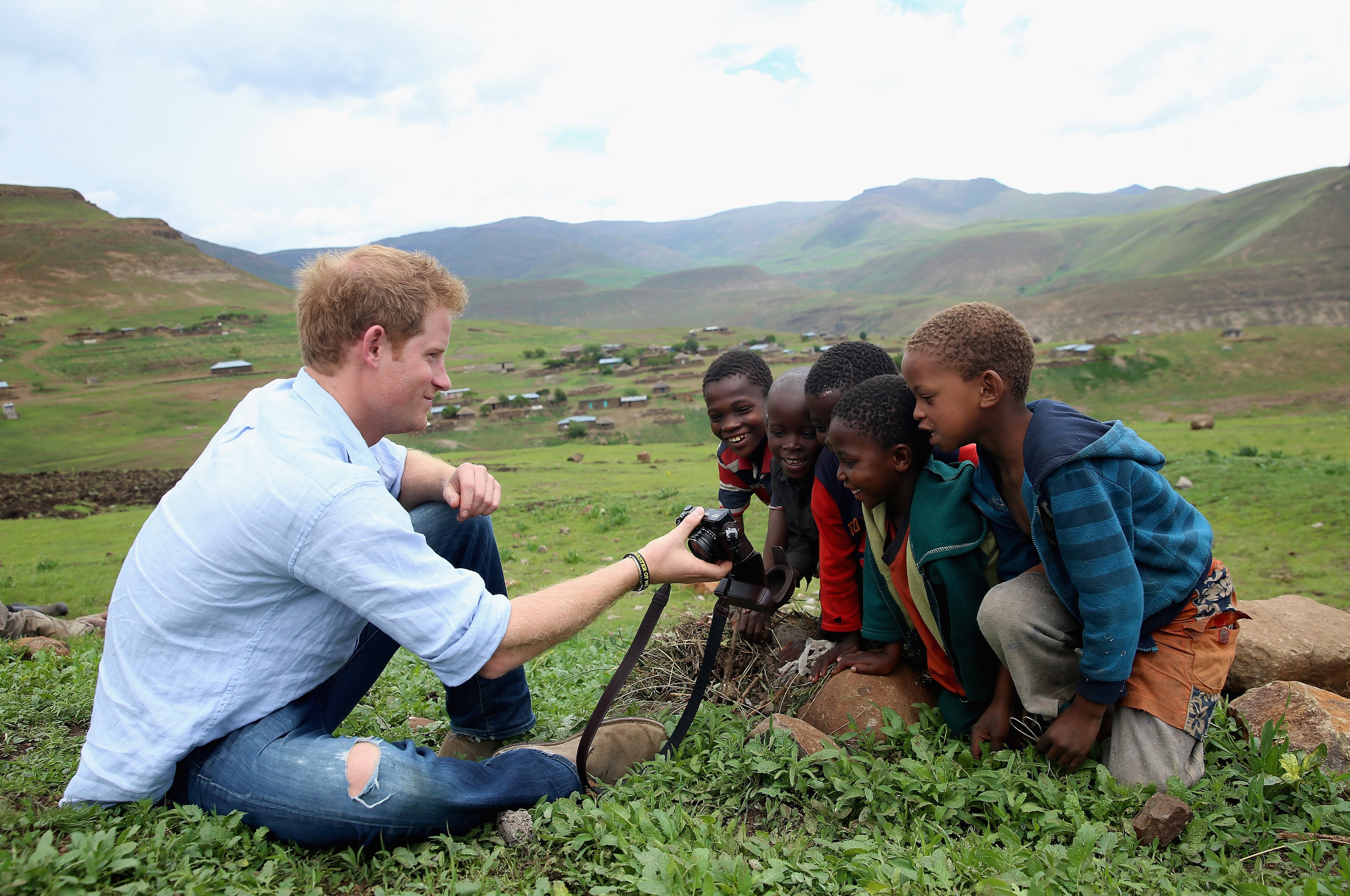Prince Harry shows children a photograph he has taken on a Fuji X100s Camera during a visit to a herd boy night school constructed by Sentebale on December 8, 2014 in Mokhotlong, Lesotho. Prince Harry was visiting Lesotho to see the work of his charity Sentebale. Sentebale provides healthcare and education to vulnerable children in Lesotho, Southern Africa. Speaking of the opportunity to document the visit himself, Prince Harry said: "I have always enjoyed photography and the challenges that come with trying to capture the perfect shot, although privately I don't take many photos. The best photos I have are in my head - I have some very special memories, mostly from Africa. But on this visit, I had the time and opportunity to be on the other side of the camera and take some photos in the stunning country of Lesotho for my charity Sentebale." (Photo by Chris Jackson - WPA Pool /Getty Images)