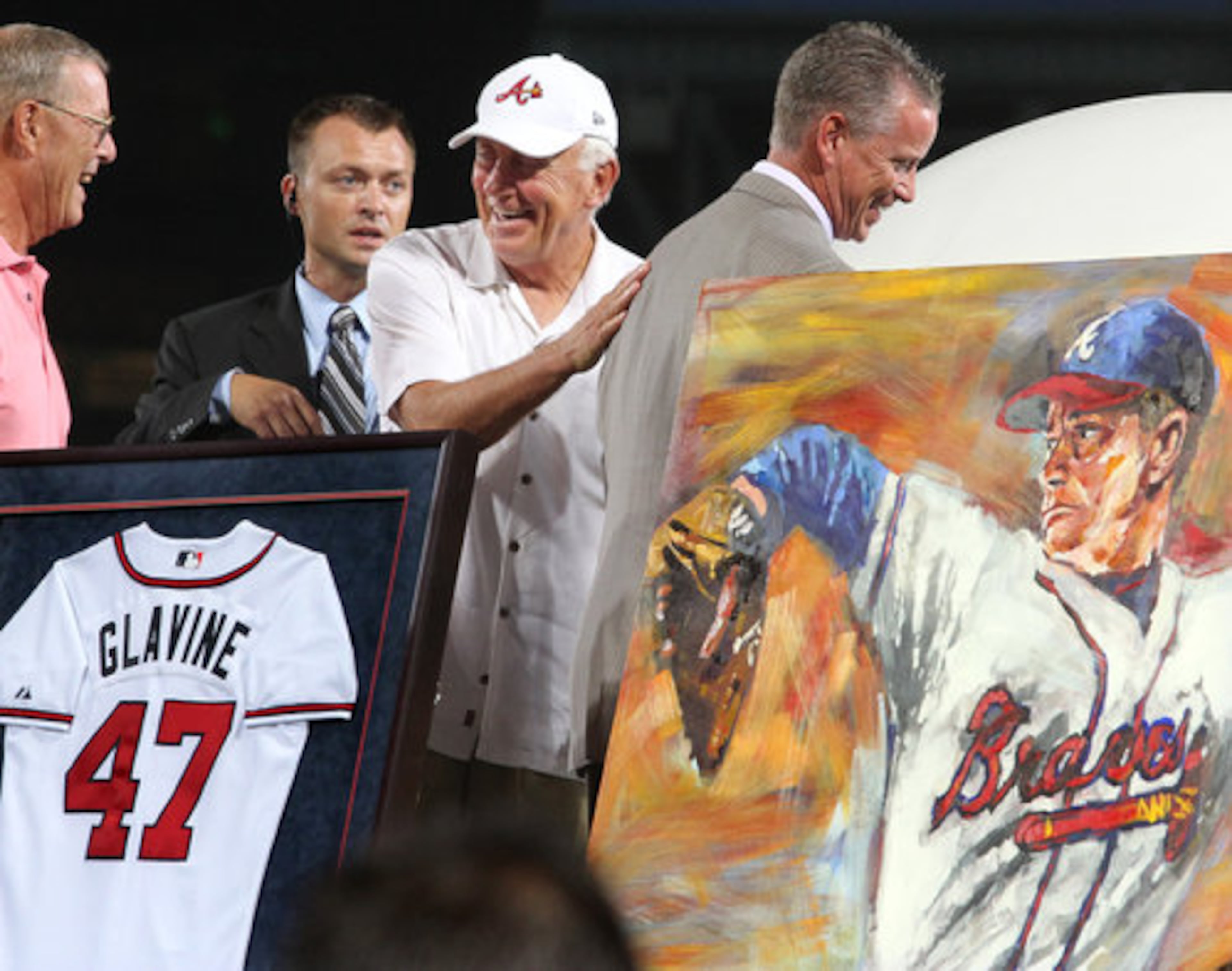 Former Braves pitcher Phil Niekro gives Tom Glavine a pat on the back during his uniform number retirement in a pre-game ceremony at Turner Field in Atlanta, Friday, August 6, 2010, before the game vs. the San Francisco Giants.