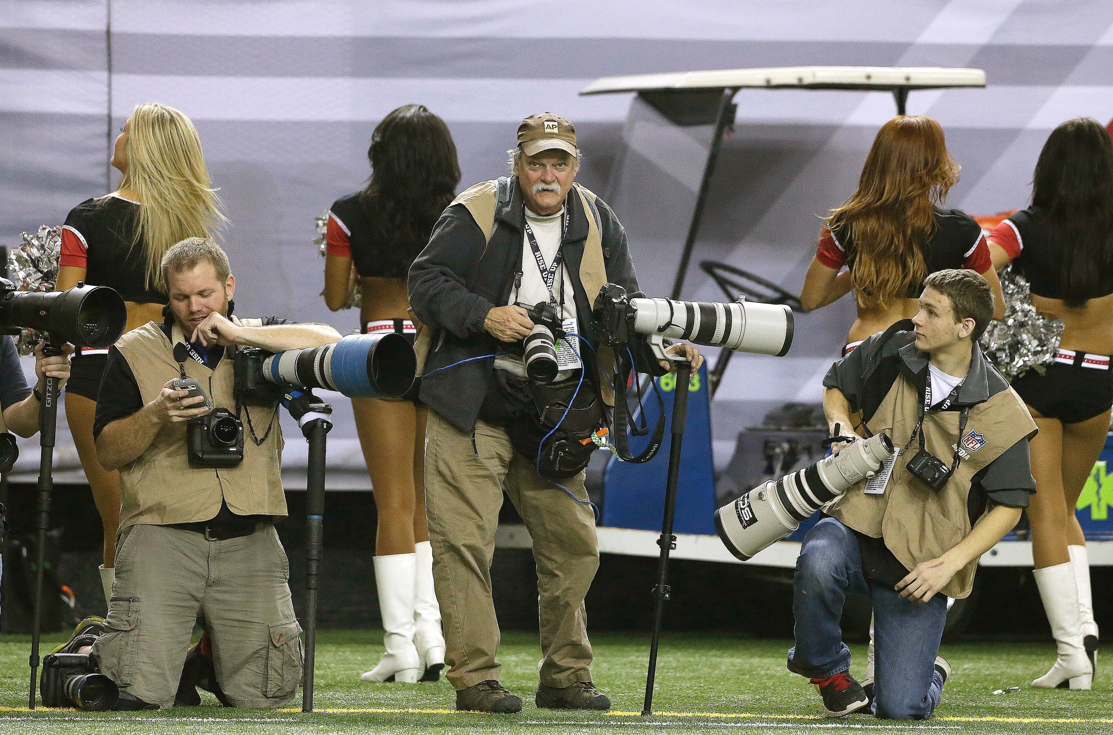 In this Sunday, Dec. 29, 2013, photo, AP Photographer Dave Martin, second from right, works during the first half of an NFL football game between the Carolina Panthers and the Atlanta Falcons, in Atlanta. Martin, a longtime Associated Press photographer based in Montgomery, Ala., died after collapsing on the Georgia Dome field at the Chick-fil-A Bowl on Tuesday, Dec. 31, 2013. Martin was 59. (AP Photo/John Bazemore)