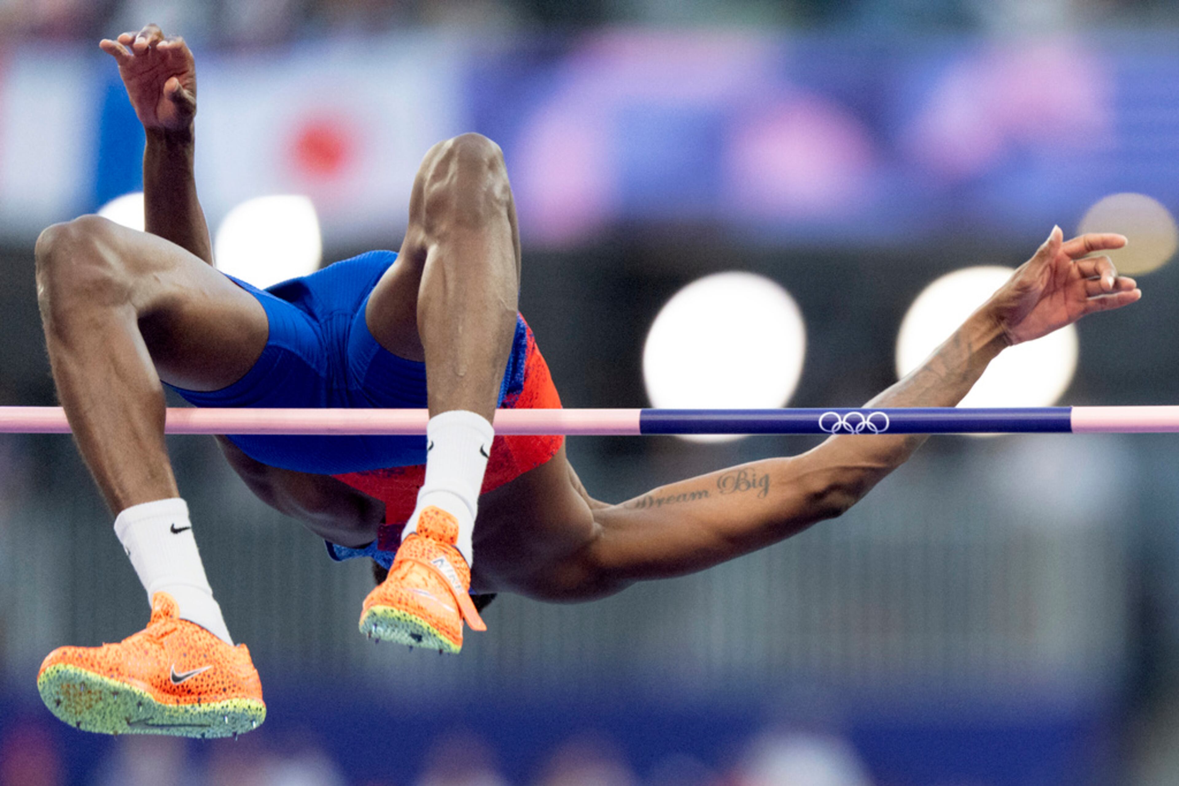 A tattoo reading "Dream Big" decorates the arm of the United States' Shelby McEwen as he clears an attempt in the men's high jump final at the 2024 Summer Olympics, Saturday, Aug. 10, 2024, in Saint-Denis, France. (AP Photo/David Goldman)