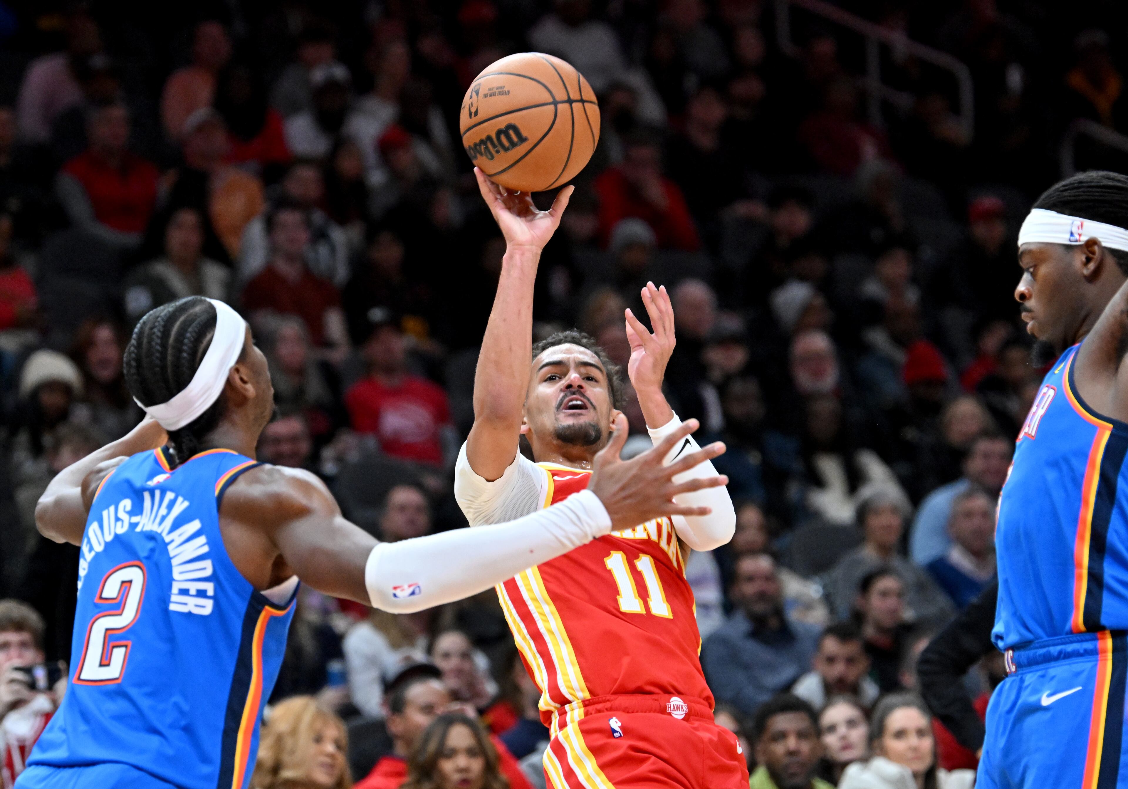 Atlanta Hawks guard Trae Young (11) gets off a shot against Oklahoma City Thunder guard Shai Gilgeous-Alexander (2) as he falls back during the first half in an NBA basketball game at State Farm Arena, Wednesday, December 3, 2024, in Atlanta. (Hyosub Shin / Hyosub.Shin@ajc.com)