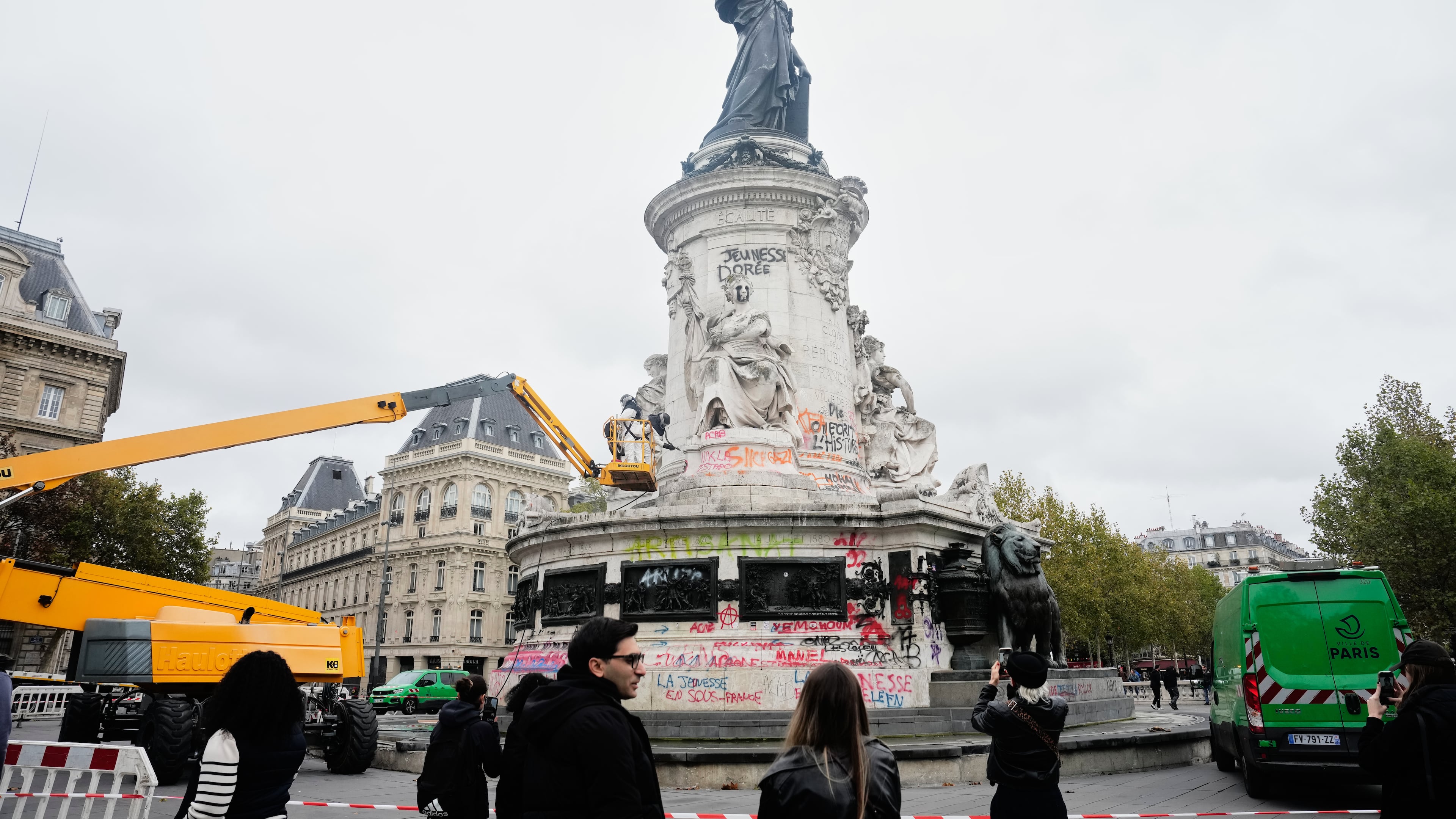 People watch and take photos of cleanup efforts after weekend protests over the cost of living turned into rioting and looting across France, in Paris, Wednesday, Oct. 21, 2026. (AP Photo/Teresa Suarez)
