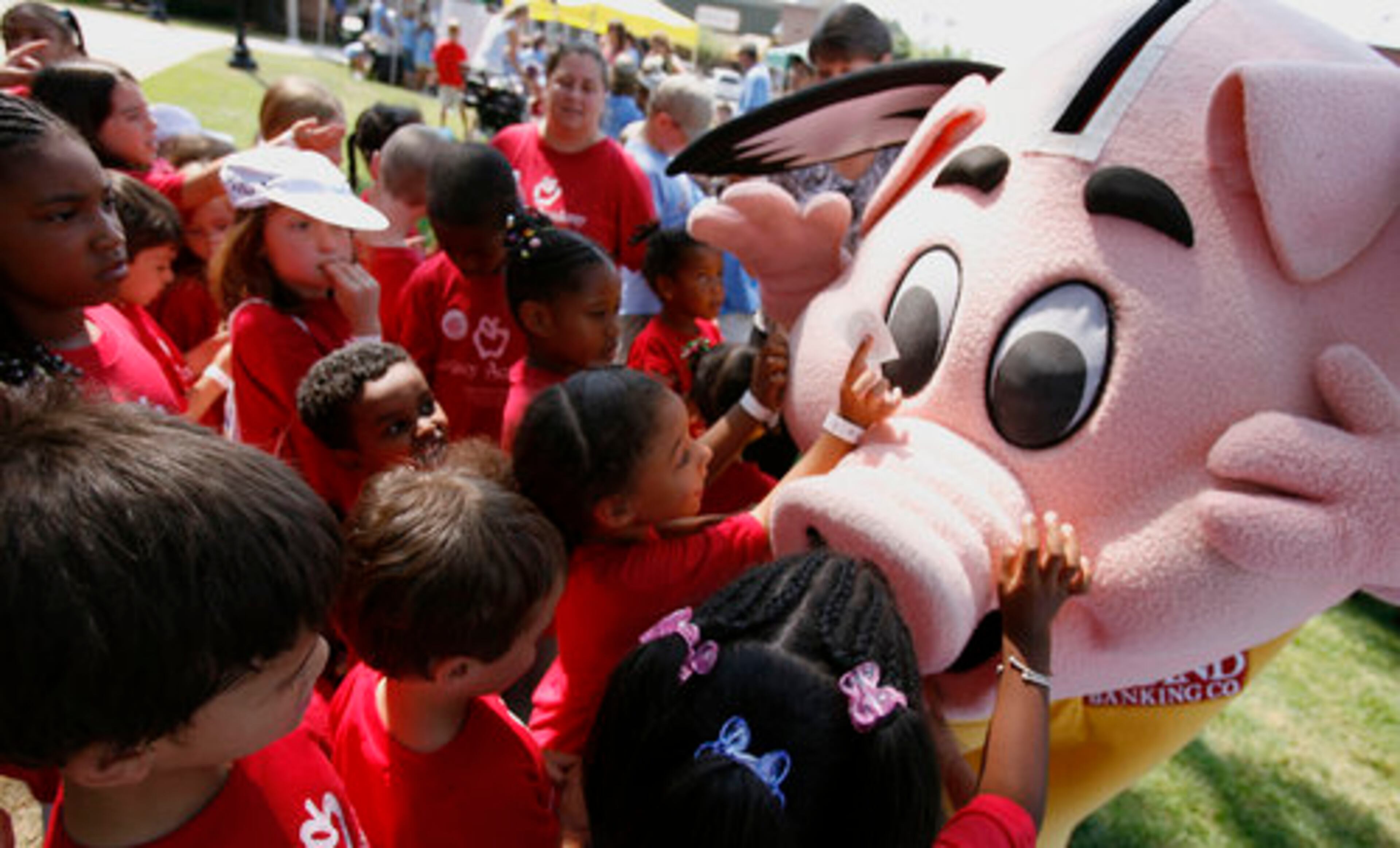 Brand Pig, the mascot for Brand Banking Company is flanked by a group of children from the Legacy Academy during the Brown Bag Concert series hosted by the Gwinnett County Parks and Recreation at the Historic Courthouse in downtown Lawrenceville Friday, June 6, 2008. Kim Shealy, Volunteer Resources and Heritage Program Coordinator said the Brown Bag Concerts have been around for over 15 years and was first started in Norcross.