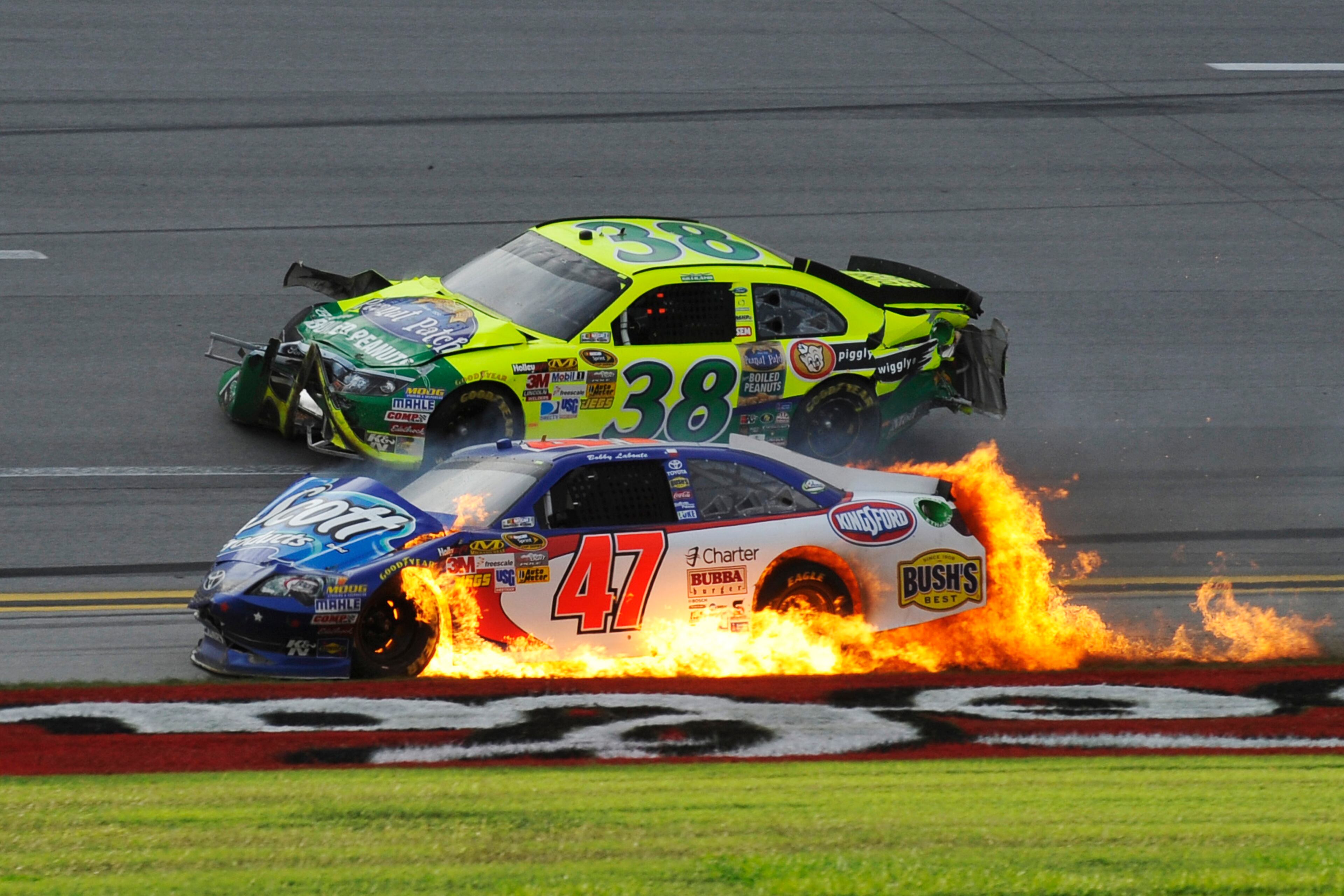 Flames engulf Bobby Labonte's car as David Gilliland (38) passes after wrecking on the last lap of the NASCAR Sprint Cup Series auto race at Talladega Superspeedway in Talladega, Ala., Sunday, Oct. 7, 2012. (AP Photo/Rainier Ehrhardt)
