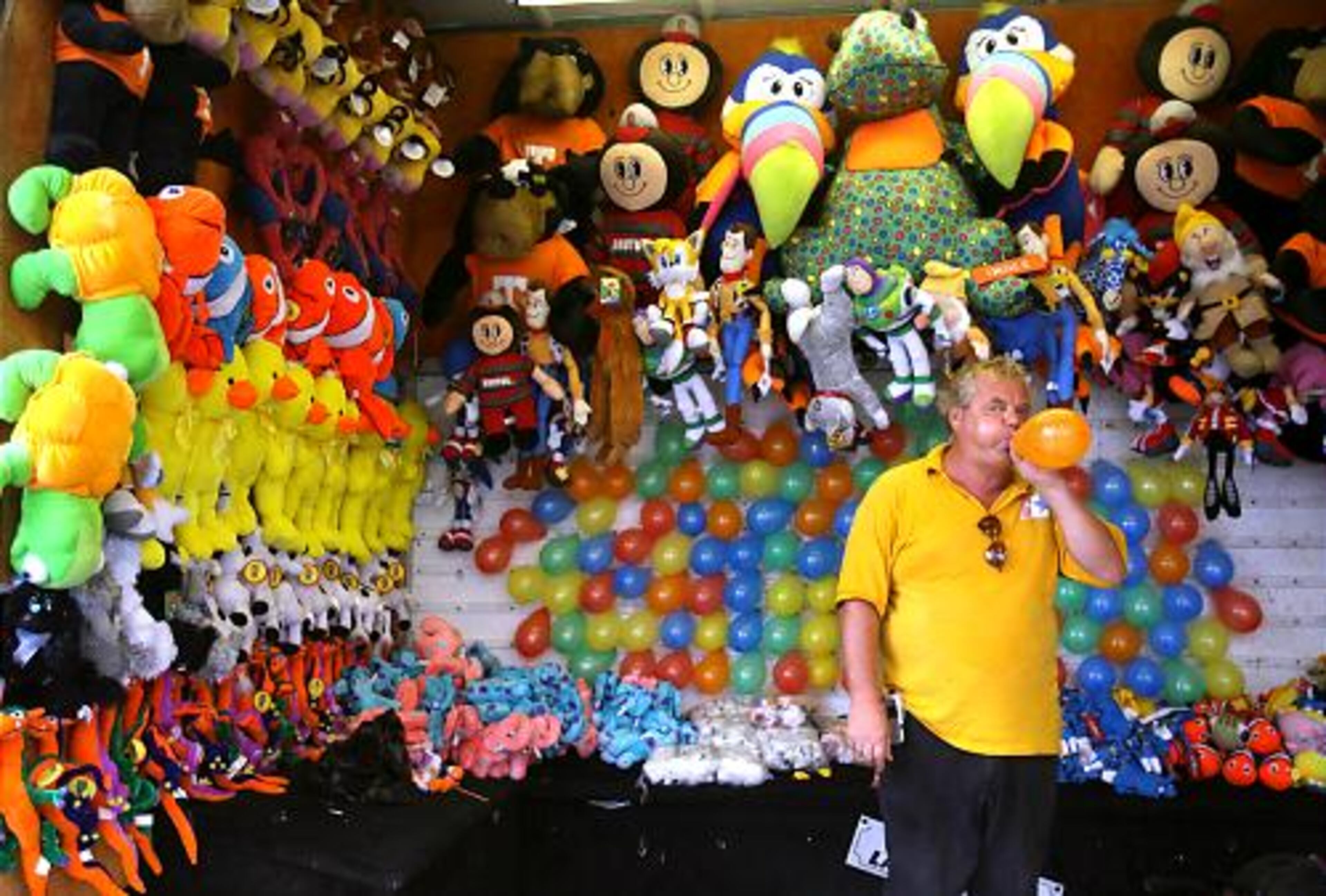 Balloon game seller Chuck Norris, of Pittsburgh, Pa., blows up a balloon in hopes of attracting some customers.