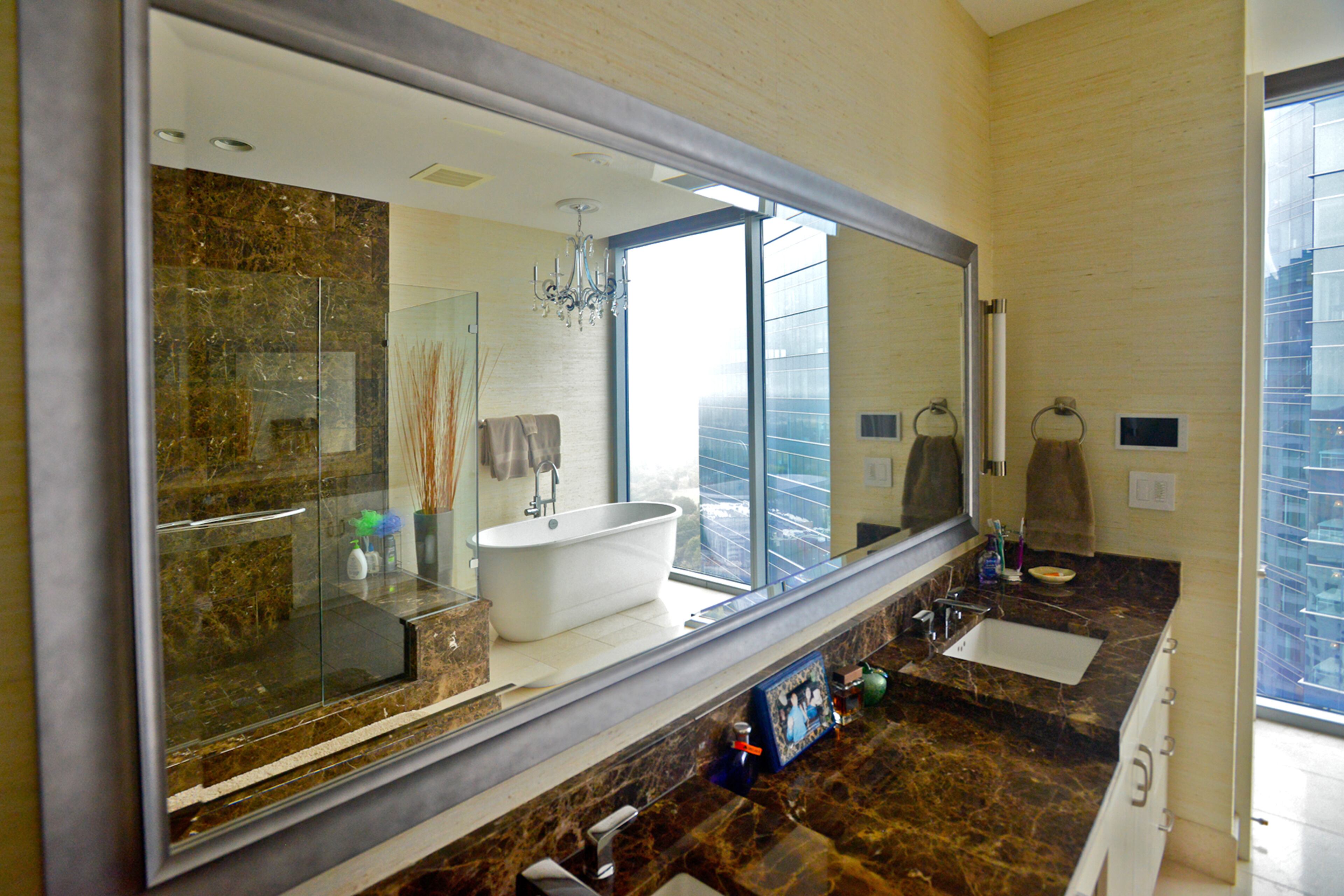 A freestanding tub and frameless glass showers are standard features in the master bathroom at 1065 Midtown. The bathrooms and rest of the condo have floor-to-ceiling glass walls.