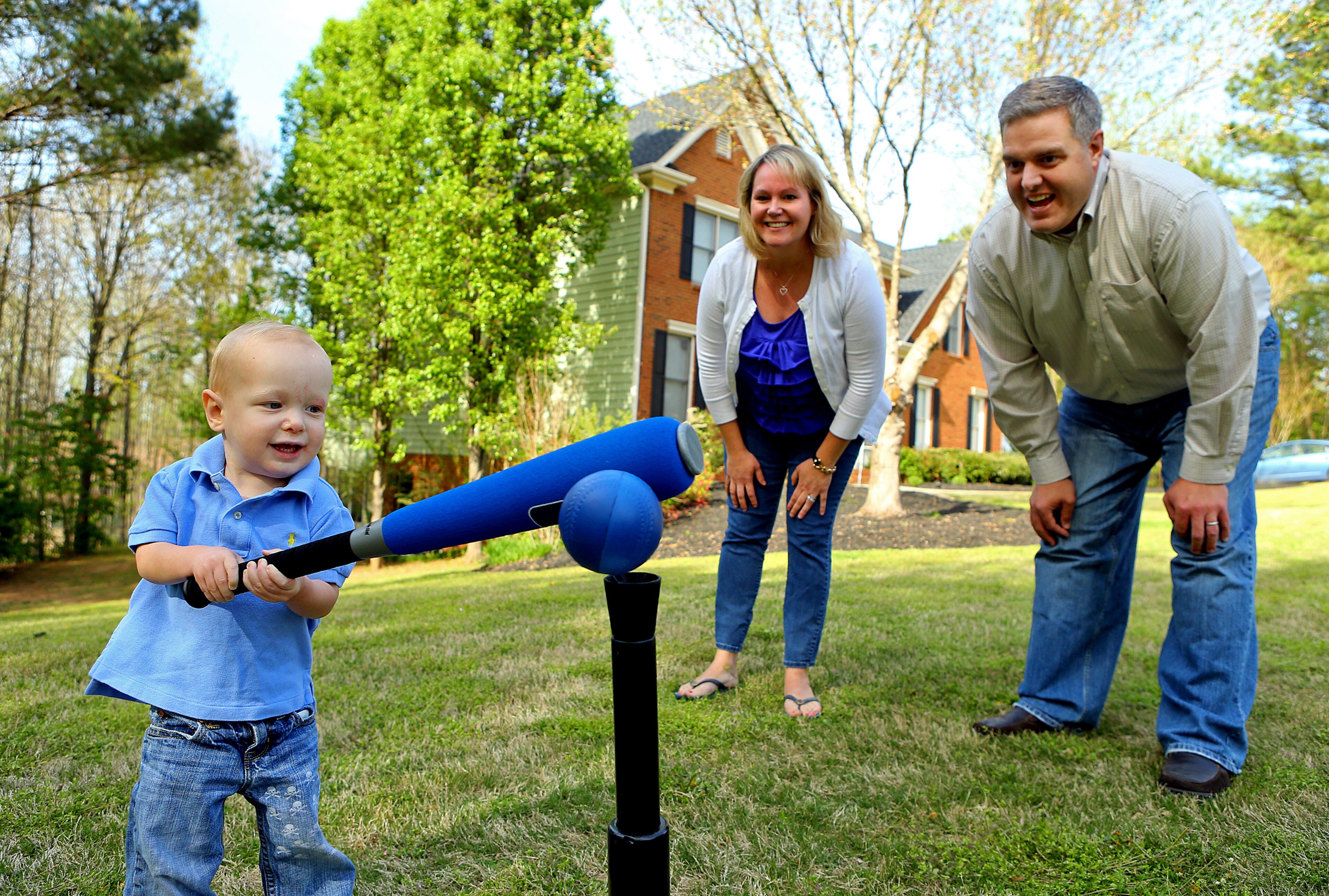 Ashley and John Shepardson look on while their 22-month-old son Zach, who has congenital heart disease, plays t-ball in the front yard of their family home in Milton. CURTIS COMPTON / CCOMPTON@AJC.COM