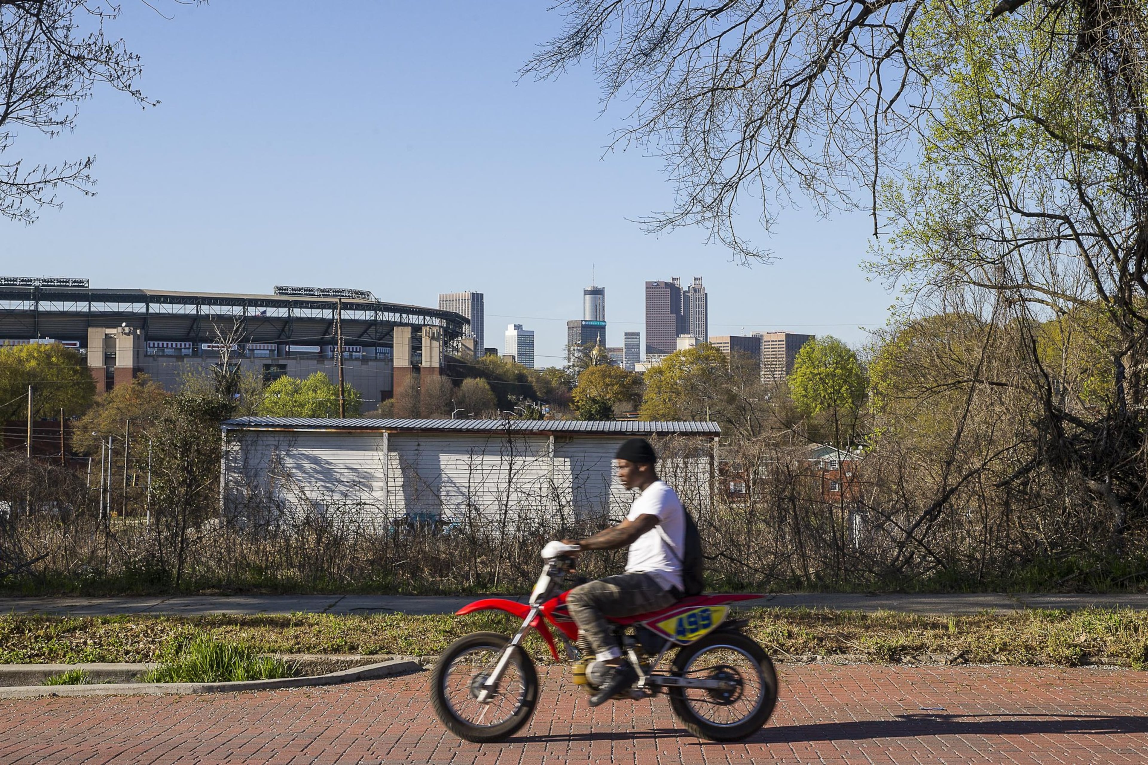 A man rides a dirt bike along brick-lined Atlanta Avenue in the Peoplestown community.