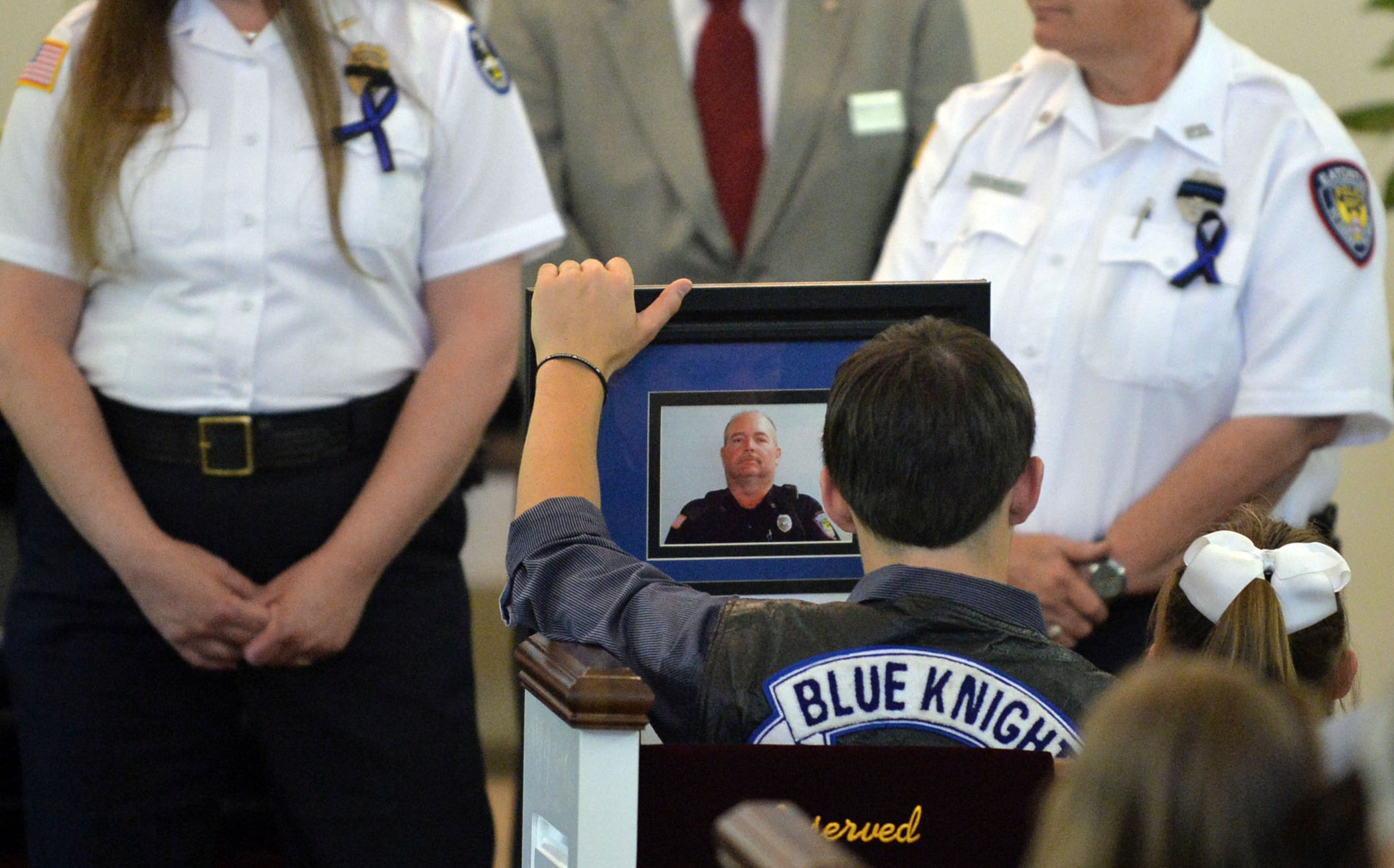 Officer Hawk's son, Zachary, holds a portrait of his father after a presentation. Officer Hawk is survived by his children: Brittany Lowrey, Taylor Talley, Heather Brandt, Victoria Hawk and Zachary Hawk. He also leaves a brother, Neal, as well as his parents, Bobby and Martha Hawk.