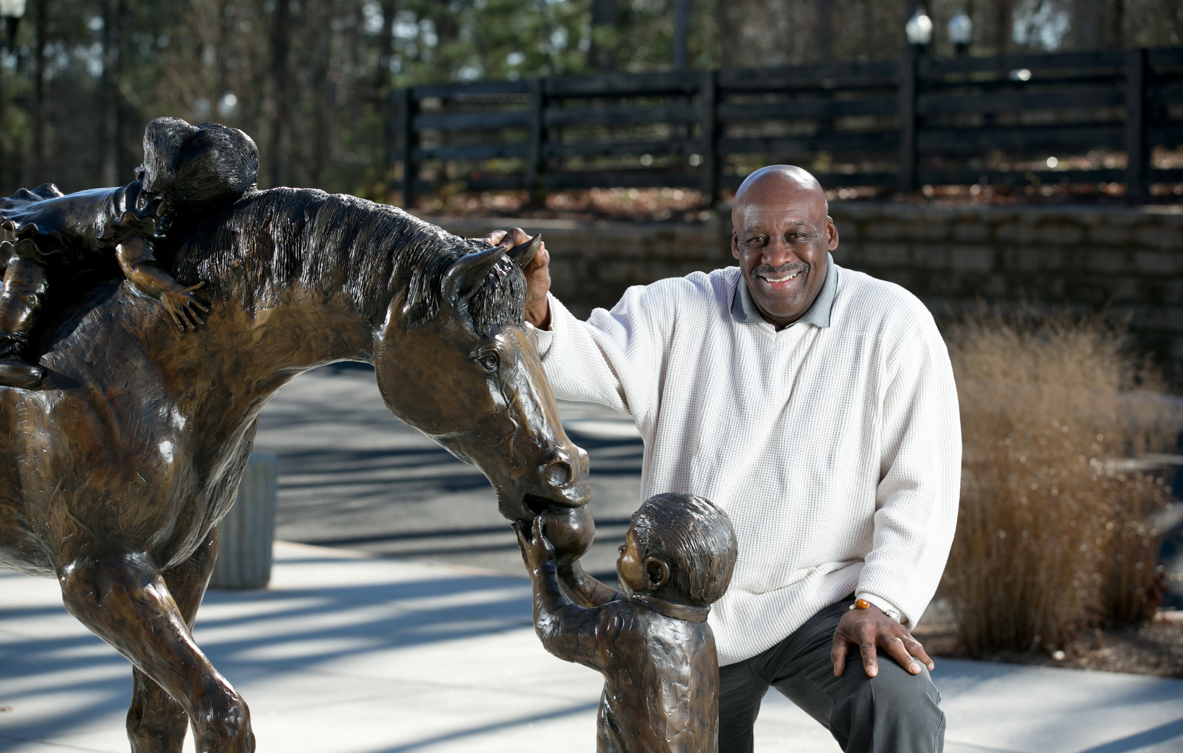 Sculptor artist George Nock is shown next to his piece, Milty, a bronze sculpture, at the Milton Library Thursday, February 4, 2016, in Milton, Ga. Nock is a former pro football player who now makes his living as a full-time artist. He drew his inspiration for this piece from the area's rural roots, kids and the pursuit of knowledge. PHOTO / JASON GETZ