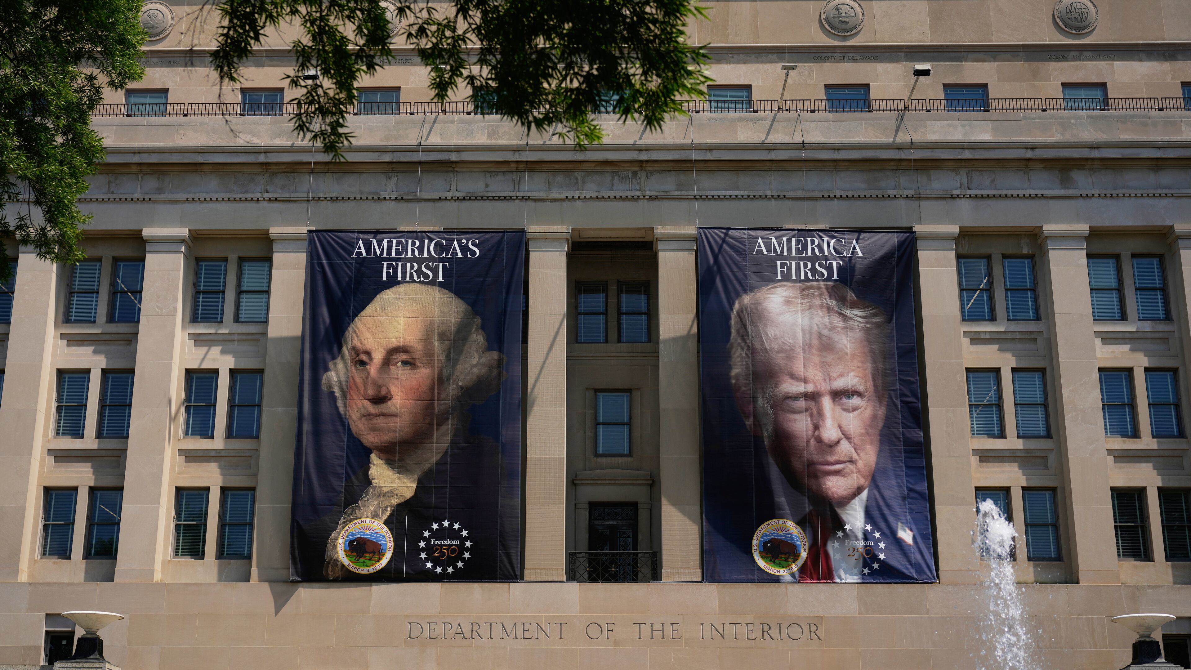 Banners, one of President George Washington that reads "America's First," left, and another of President Donald Trump that reads, "America First," are pictured at the Department of the Interior, Thursday, June 25, 2026, in Washington. (AP Photo/Carolyn Kaster)