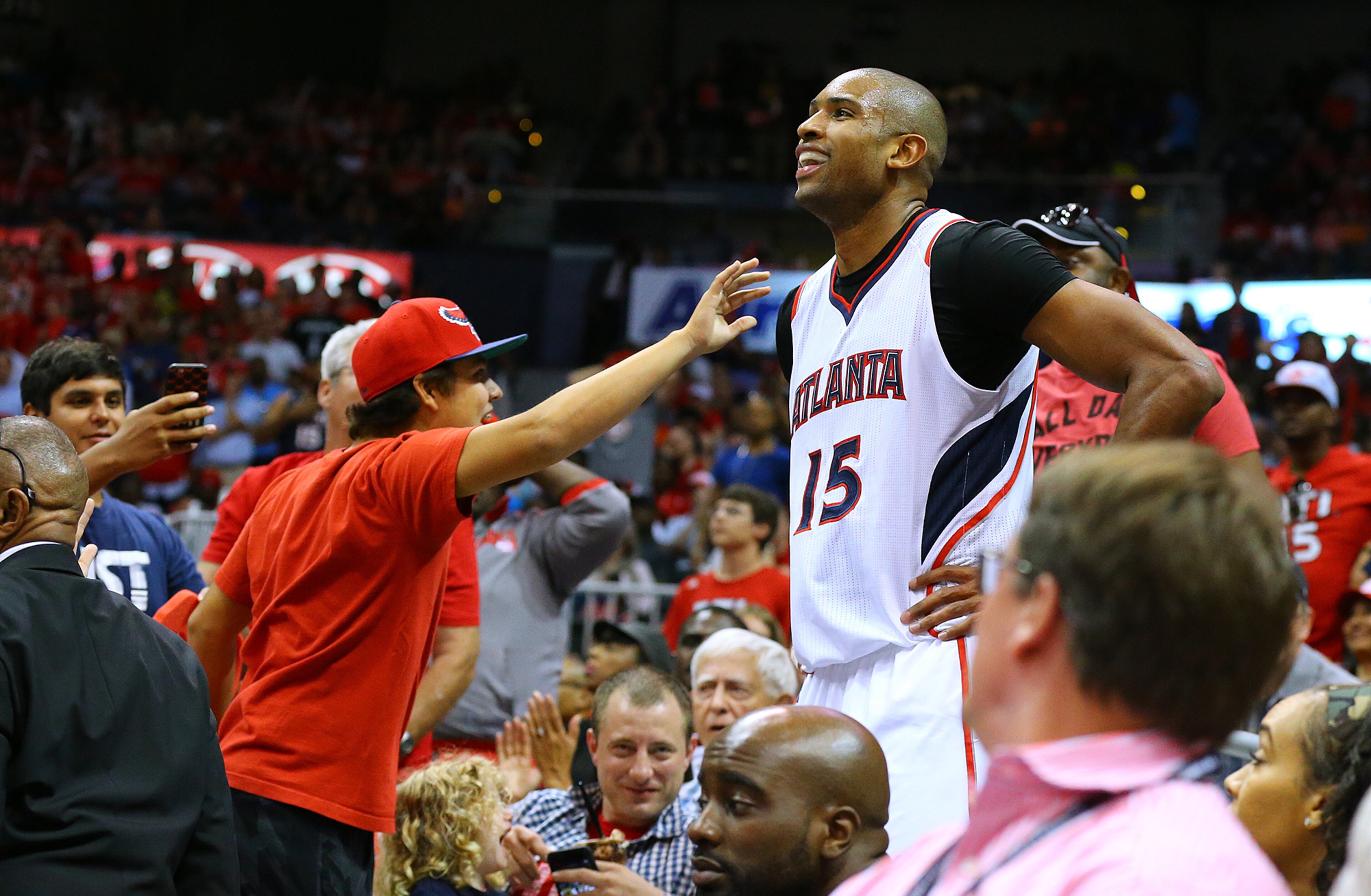 Hawks center Al Horford can only smile as he ends up several rows back into the stands after being called for a foul on Tuesday, May 5, 2015 in Atlanta. Curtis Compton / ccompton@ajc.com