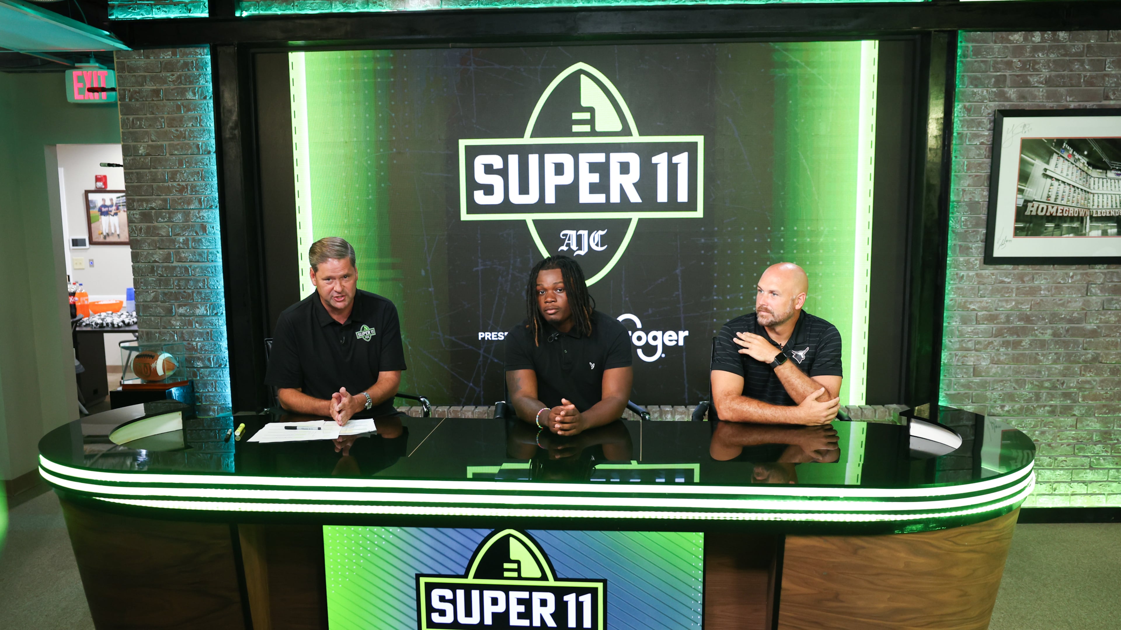 DawgNation’s Brandon Adams interviews Kell’s Quinterrius “Moonie” Gipson and coach Bobby May during the taping of the Super 11 reveal show at Score ATL in Roswell on Aug. 3, 2026. (Arvin Temkar/AJC)