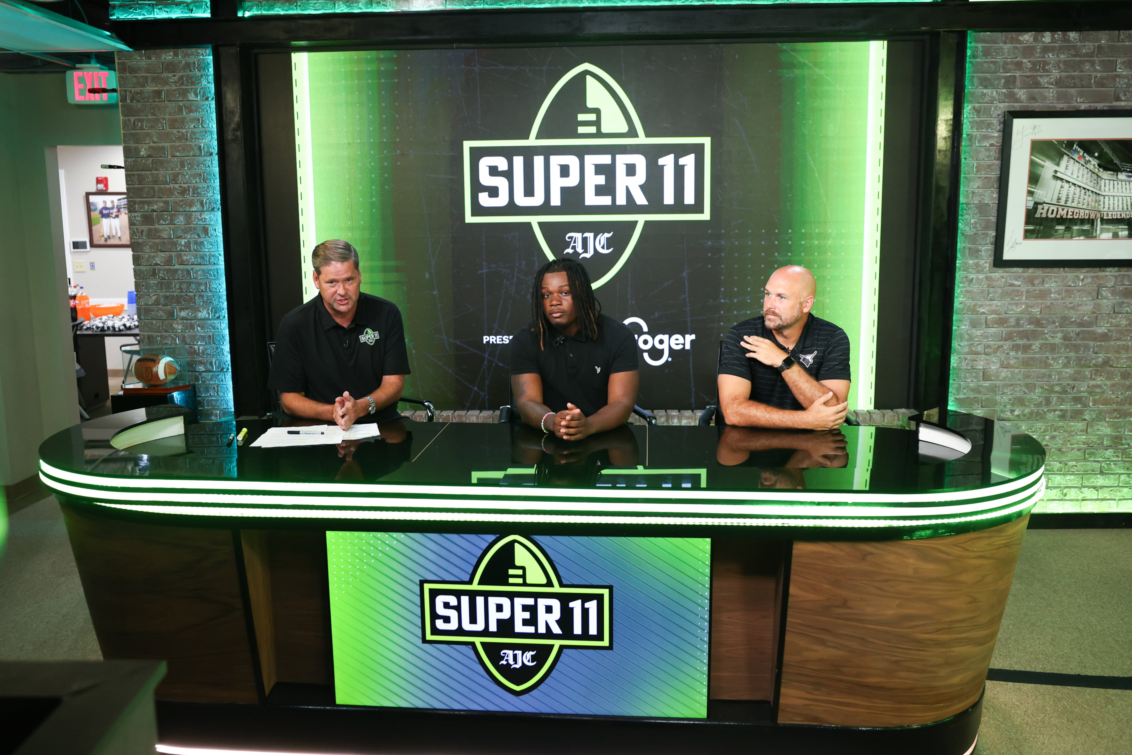 DawgNation’s Brandon Adams interviews Kell’s Quinterrius “Moonie” Gipson and coach Bobby May during the taping of the Super 11 reveal show at Score ATL in Roswell on Aug. 3, 2026. (Arvin Temkar/AJC)