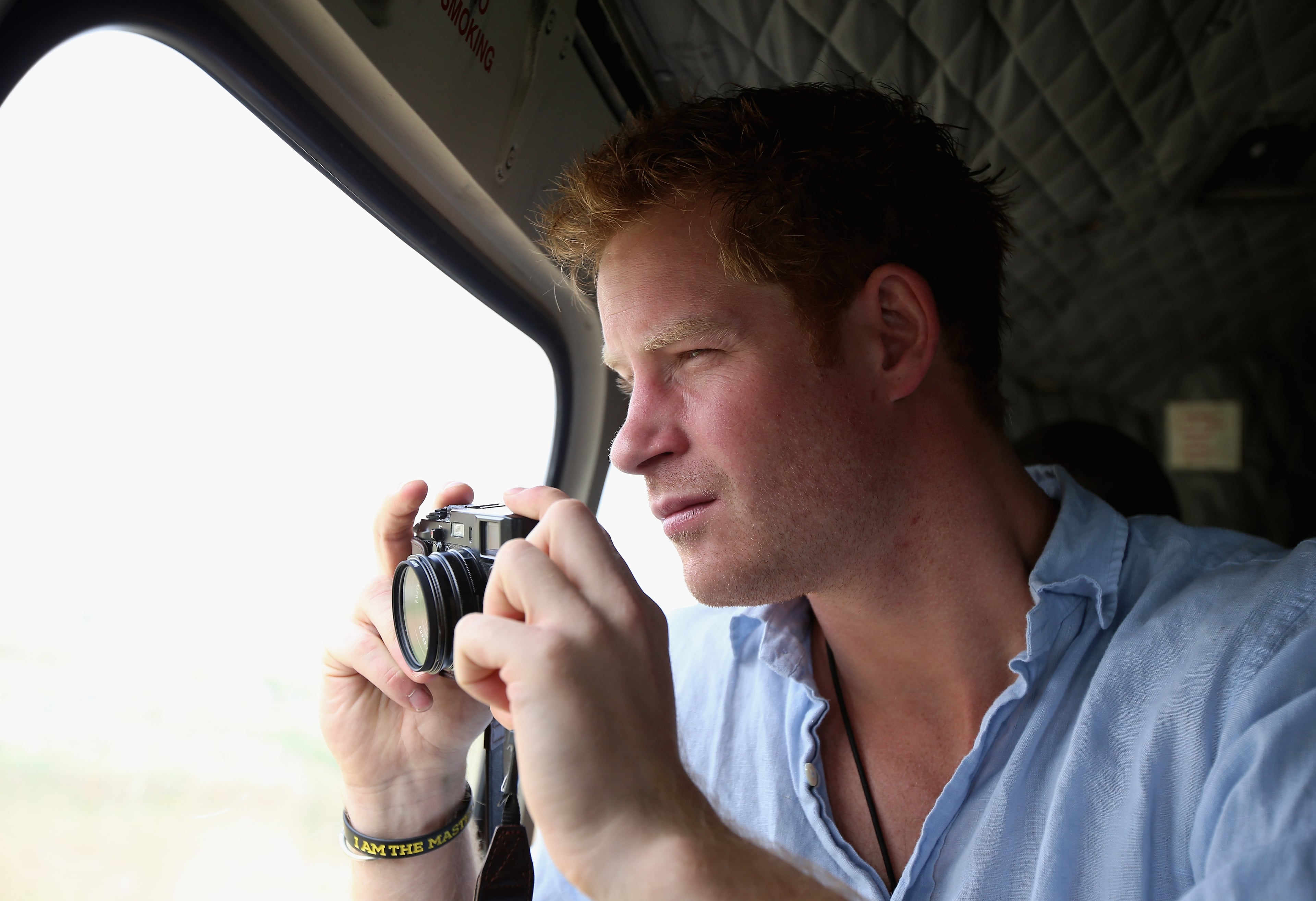 Prince Harry takes a photograph out of the window of a Lesotho Army Helicopter on a Fuji X100s Camera as he travels over the Muluti Mountains on the way to a herd boy night school constructed by Sentebale on December 8, 2014 in Mokhotlong, Lesotho. Prince Harry was visiting Lesotho to see the work of his charity Sentebale. Sentebale provides healthcare and education to vulnerable children in Lesotho, Southern Africa. Speaking of the opportunity to document the visit himself, Prince Harry said: "I have always enjoyed photography and the challenges that come with trying to capture the perfect shot, although privately I don't take many photos. The best photos I have are in my head - I have some very special memories, mostly from Africa. But on this visit, I had the time and opportunity to be on the other side of the camera and take some photos in the stunning country of Lesotho for my charity Sentebale." (Photo by Chris Jackson - WPA Pool /Getty Images)