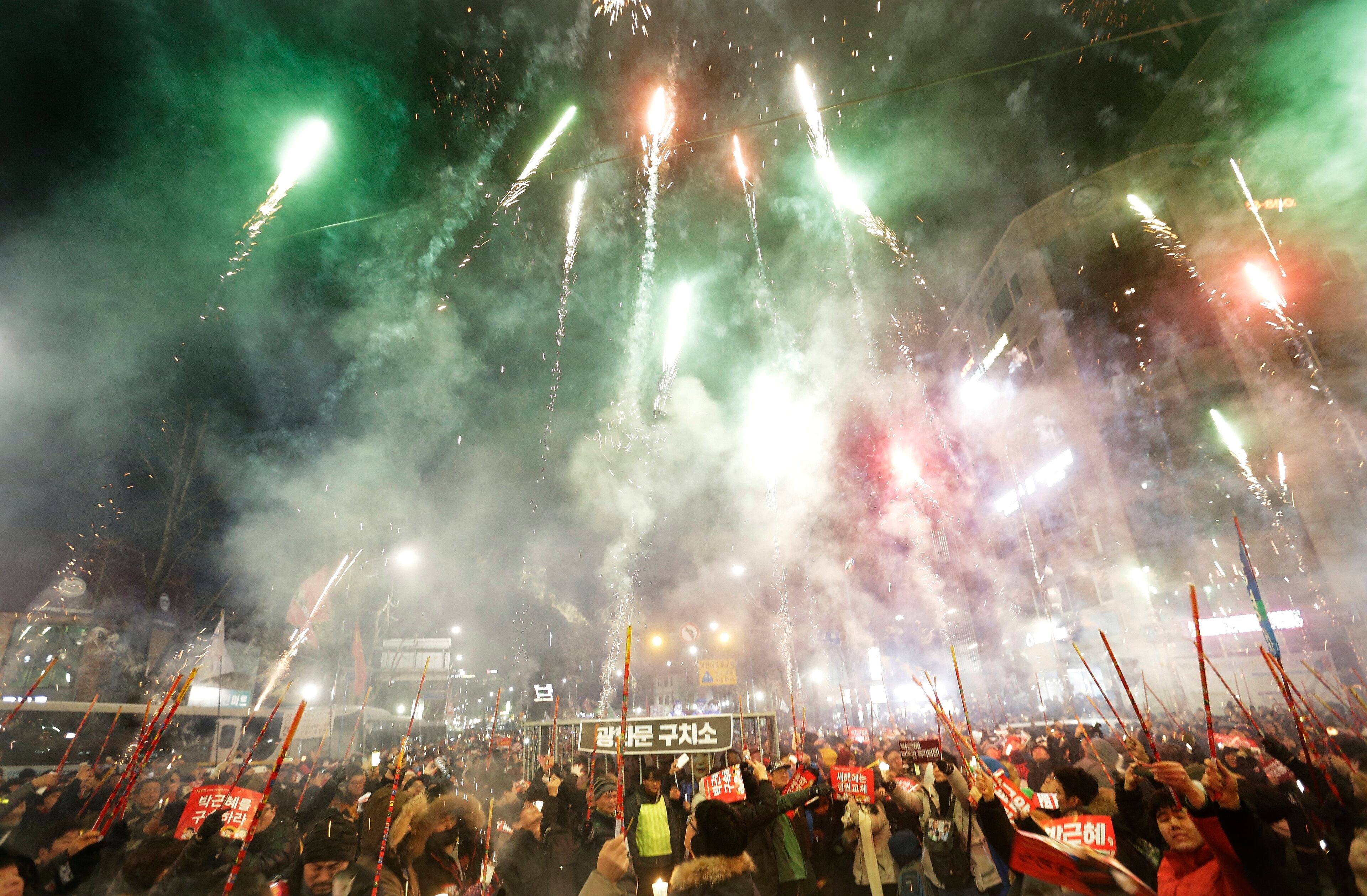 Protesters set off fireworks during a candle light vigil calling for impeached President Park Geun-hye to step down, near the presidential house in Seoul, South Korea, Saturday, Dec. 31, 2016. Even on New Year's Eve, large crowds of South Koreans gathered to join another rally demanding the ouster of Park, who's determined to restore her powers through a court trial. (AP Photo/Ahn Young-joon)