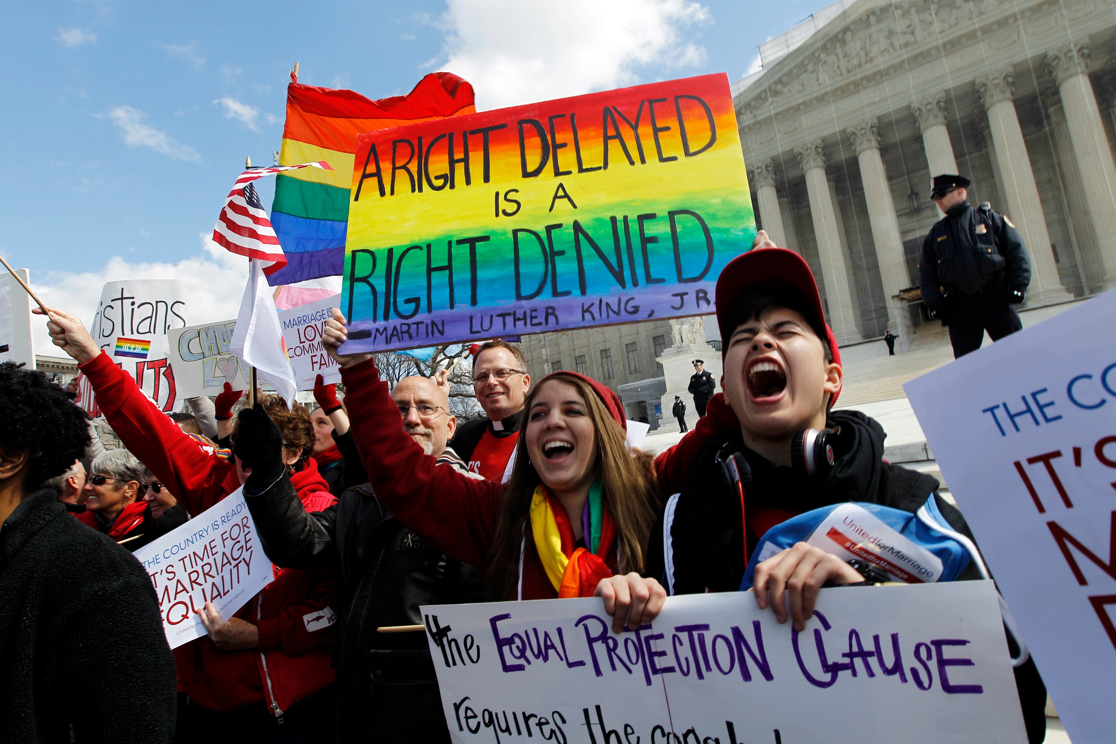 In this photo taken Wednesday, March 27, 2013, demonstrators holding flags chants in front of the Supreme Court in Washington. The U.S. Supreme Court, in the second day of gay marriage cases, turned Wednesday to a constitutional challenge to the federal law that prevents legally married gay Americans from collecting federal benefits generally available to straight married couples.