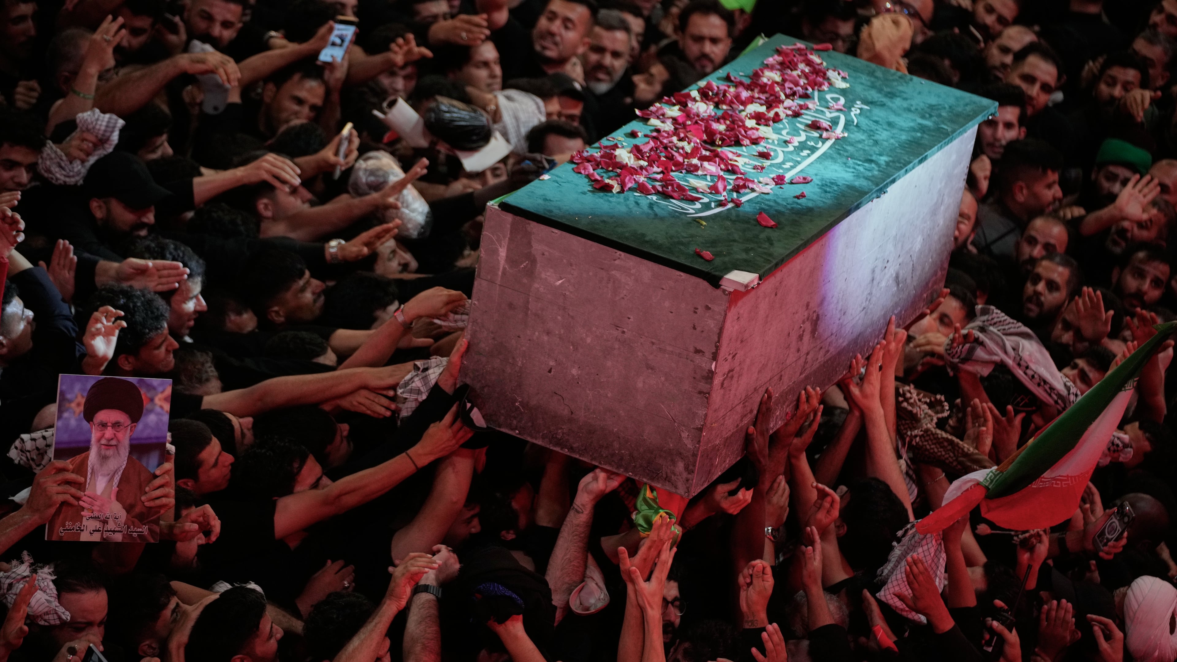 The flower petal-covered coffin of the late Iranian Supreme Leader Ayatollah Ali Khamenei is carried above mourners reaching out to touch it outside the Imam Hussein Shrine in Karbala, Iraq, early Thursday, July 9, 2026. (AP Photo/Khalil Hamra)